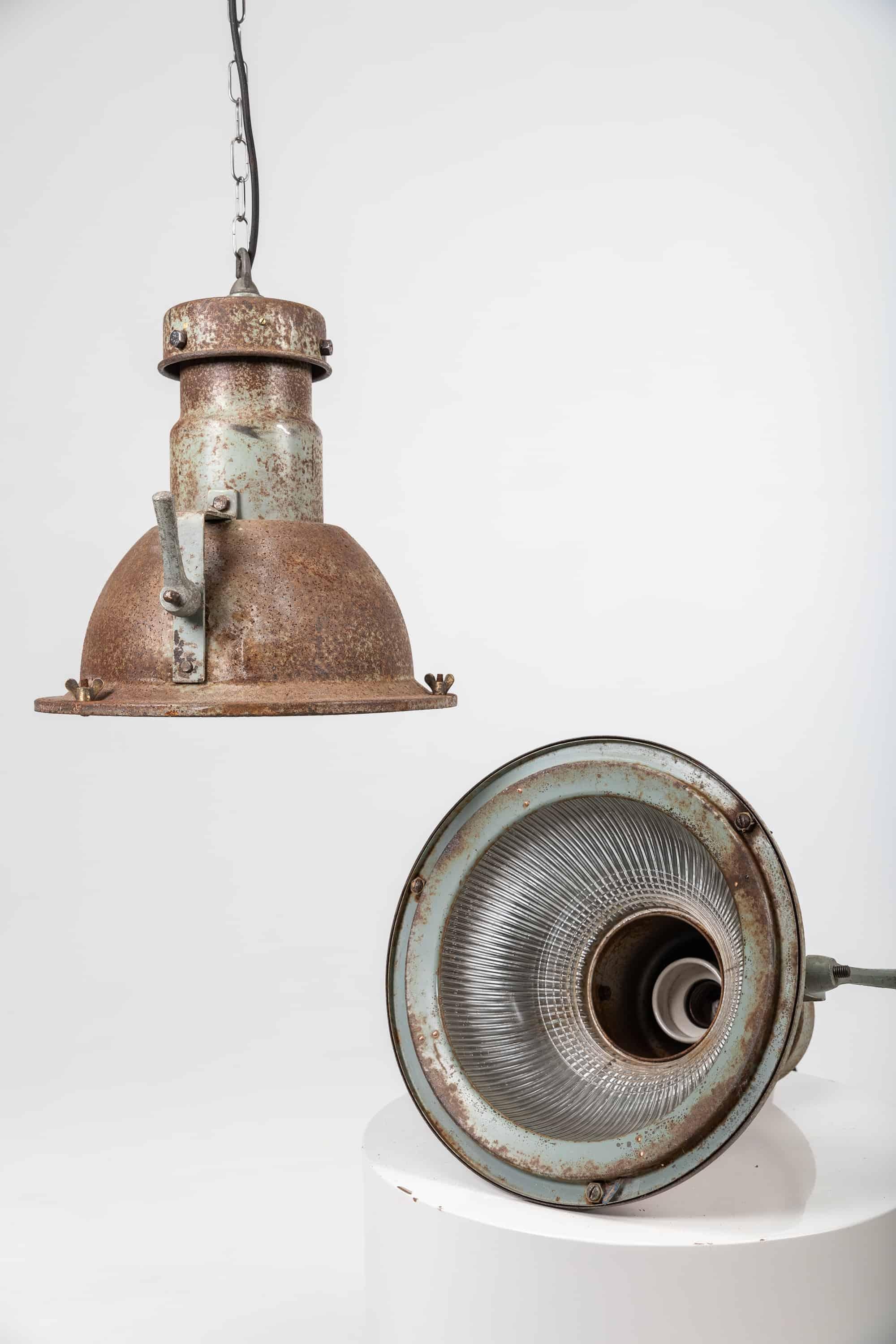 Industrial steel pendant lamps with glass inserts made in England by Holophane. c.1940

A heavy but charming patina covers the lamps. The prismatic glass inserts made famous by Holophane are marked with the makers name on the inside rim. Priced