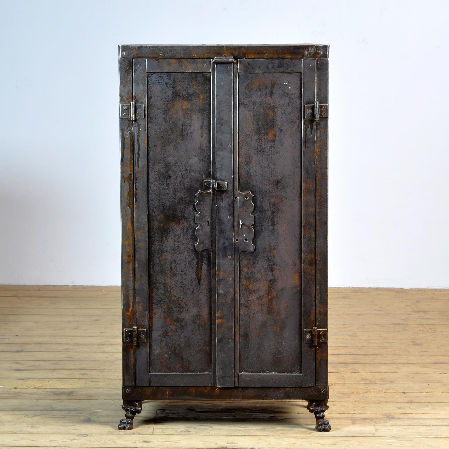 Riveted industrial cabinet, circa 1910. The cabinet is made with beautiful details and cast iron legs in the shape of a lion's paw. Exceptionally graceful for a factory cabinet. The cabinet comes with four glass shelves. The space between the