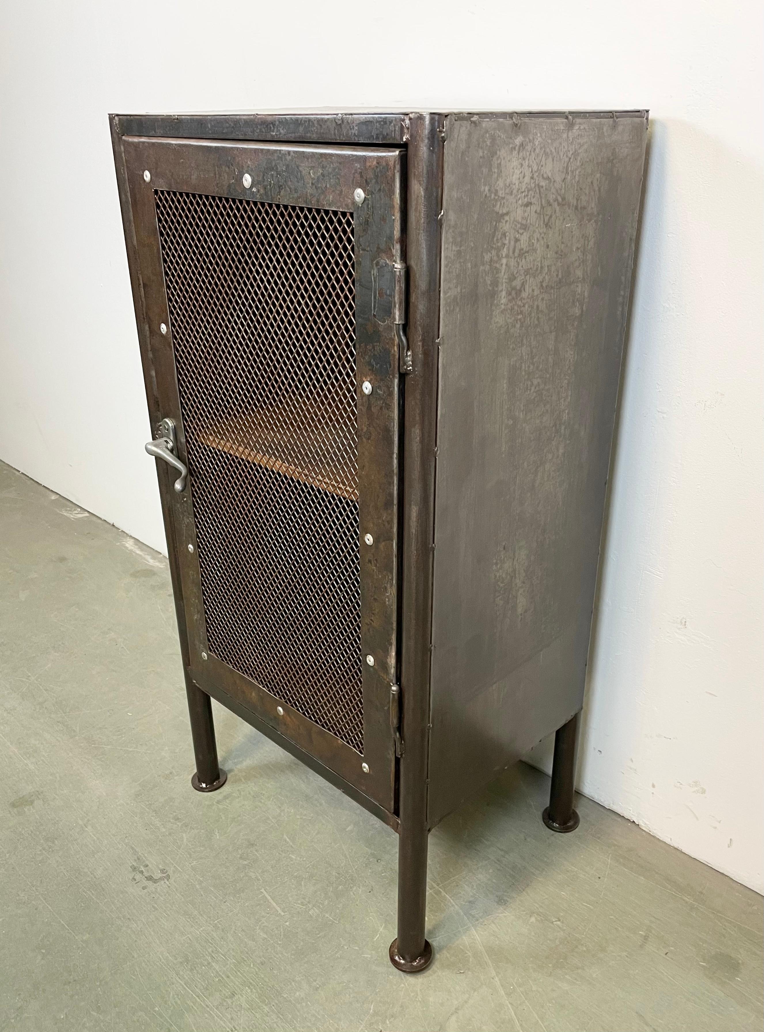 Iron cabinet from the 1960s it features an iron construction, mesh door and one wooden shelf inside the cabinet. The weight of the cabinet is 35 kg.