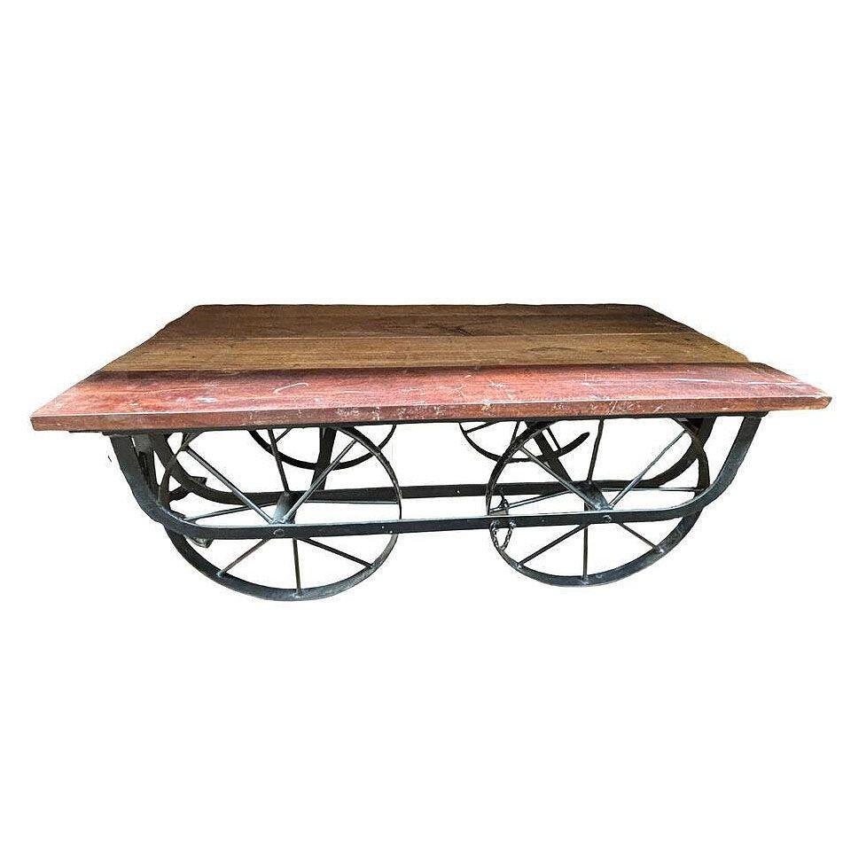 Der Couchtisch aus Eisen und wiederverwertetem Holz, der den Trolly-Wagen der Eisenbahn von früher nachempfunden ist, besticht durch eine Mischung aus mehrfarbigen Holzelementen, die einen reichen Patchwork-Effekt erzeugen. Die Platte aus Altholz