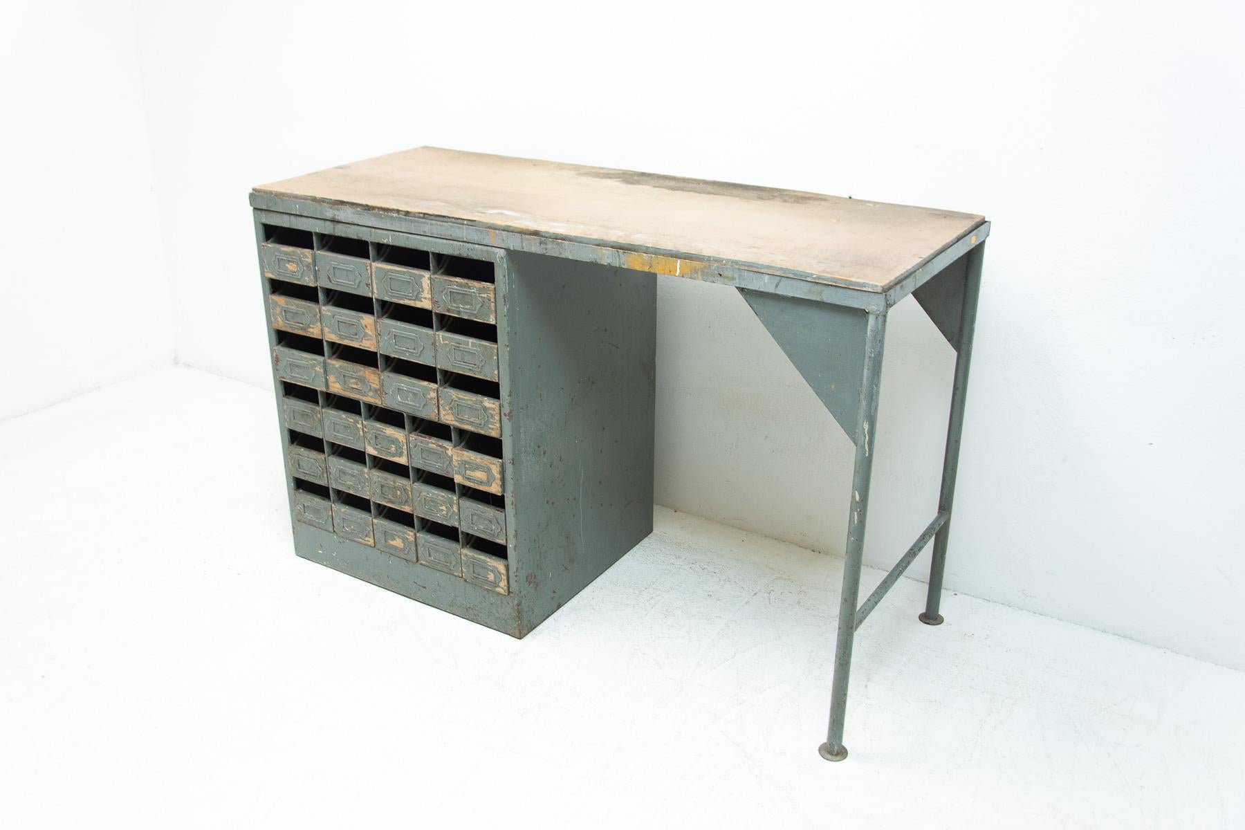 This industrial workbench was made in the former Czechoslovakia in the 1950´s

This desk was originally used as a work table for craftsmen, can also be used as a desk. It´s made of iron with formica on the table top. There are 24 drawers under the