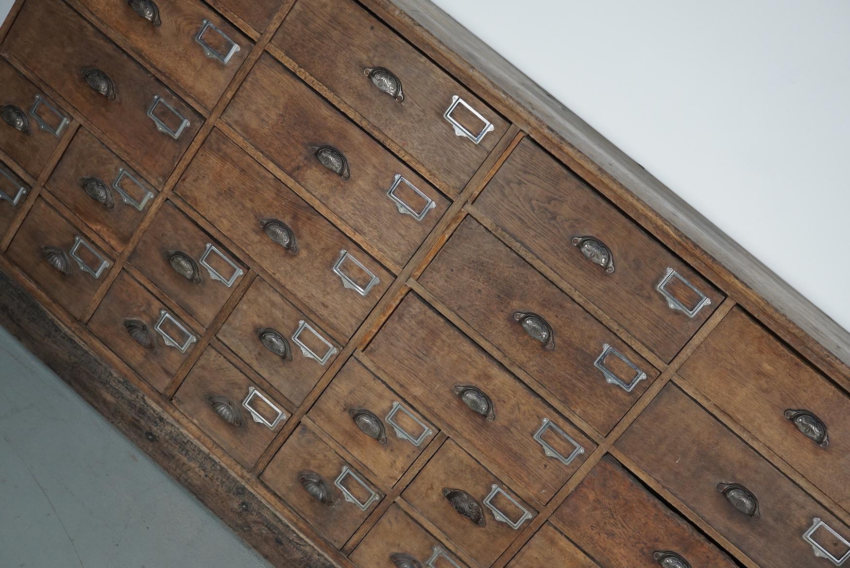 This large hardware store cabinet was made around the 1920/1930s in France from oak. It features 15 large drawers with ornate cast iron handles and 20 smaller ones. The interior dimensions of the drawers are: DWH 34 x 42 x 13.5 cm and DWH 34 x 19 x