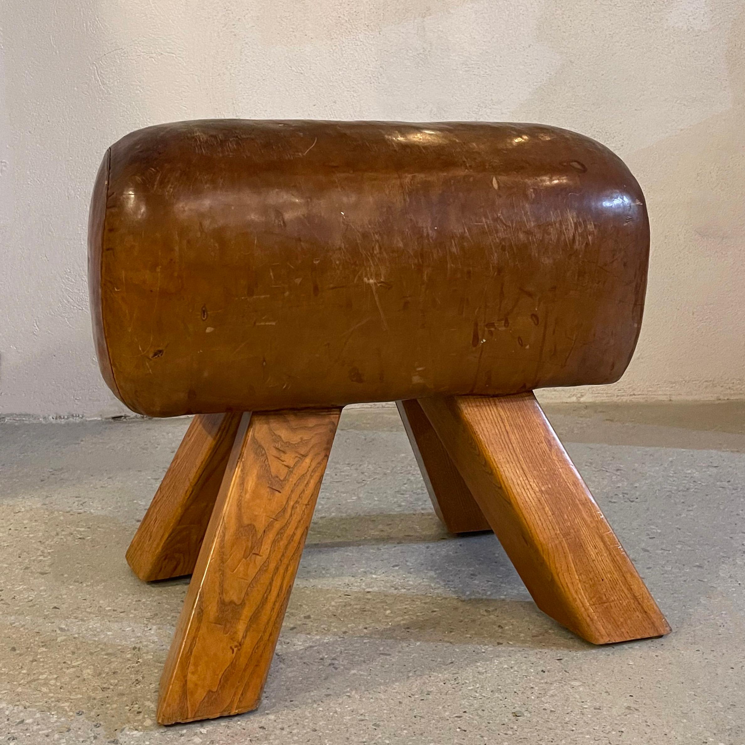 Vintage, industrial, gymnastic, leather, pommel horse bench or ottoman circa 1940's features a wonderfully patinated, rust brown leather seat showing off it's original history with oak legs. A fantastic, rustic industrial edition to an entryway or