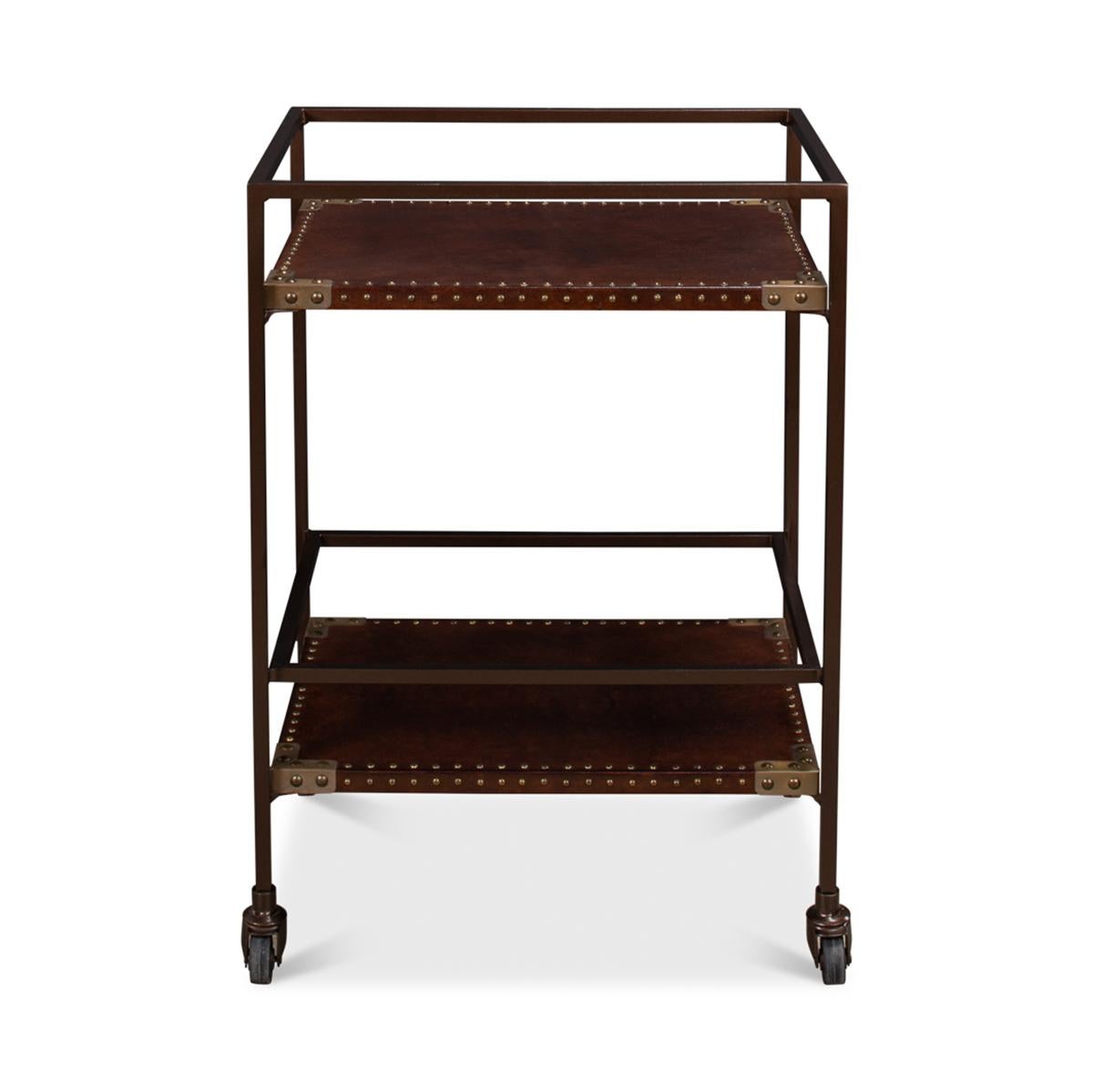 An Industrial leather trolley or bar cart with a bronzed metal frame with two leather-wrapped shelves with nailhead trim on large caster feet.

Dimensions: 18