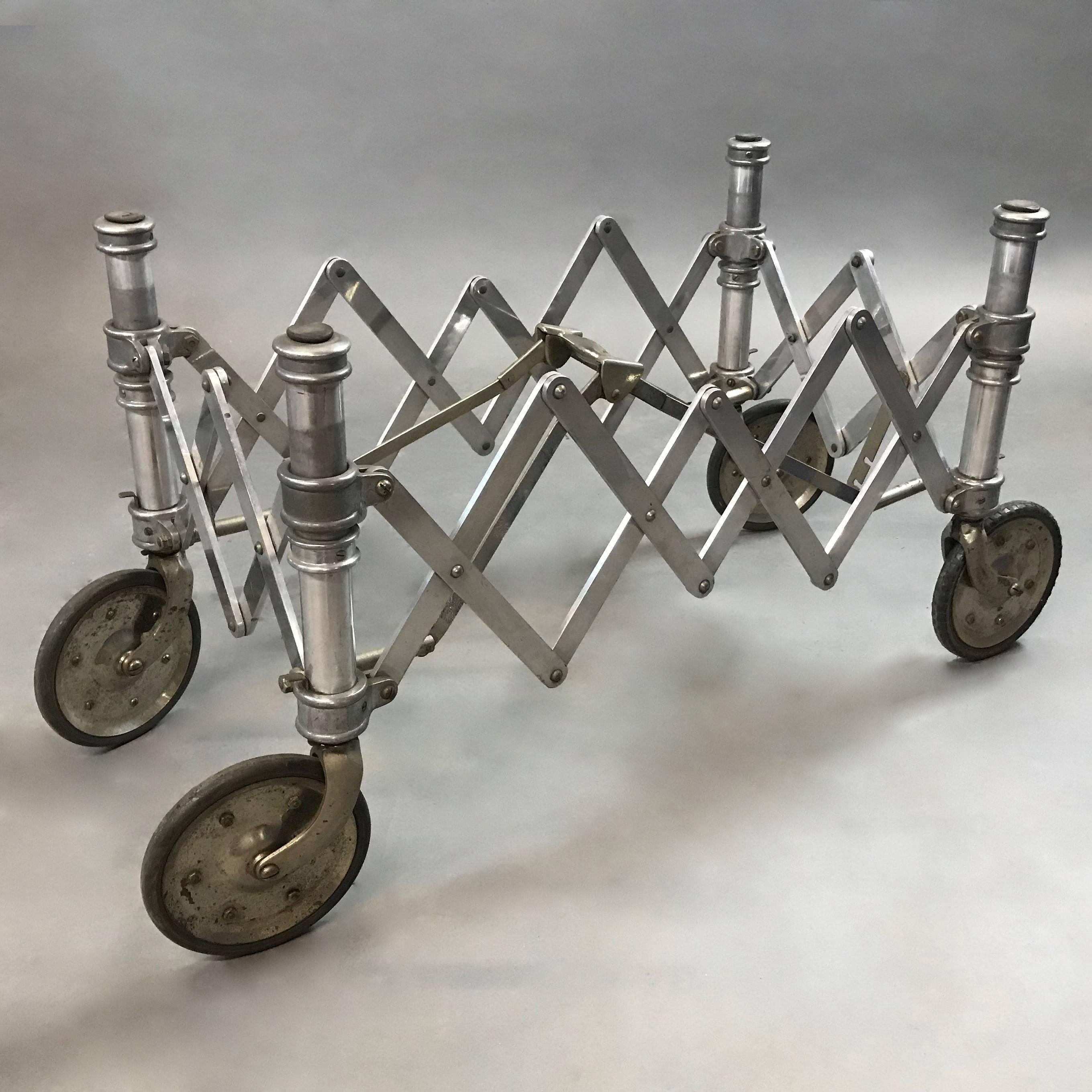 Industrial, machine-age, aluminum, accordion base, church truck, gurney expands to 33in x 18in x 20.5in height to make a wonderful coffee table base. The piece locks into place once the handle is fully depressed and features rubber bumpers on the