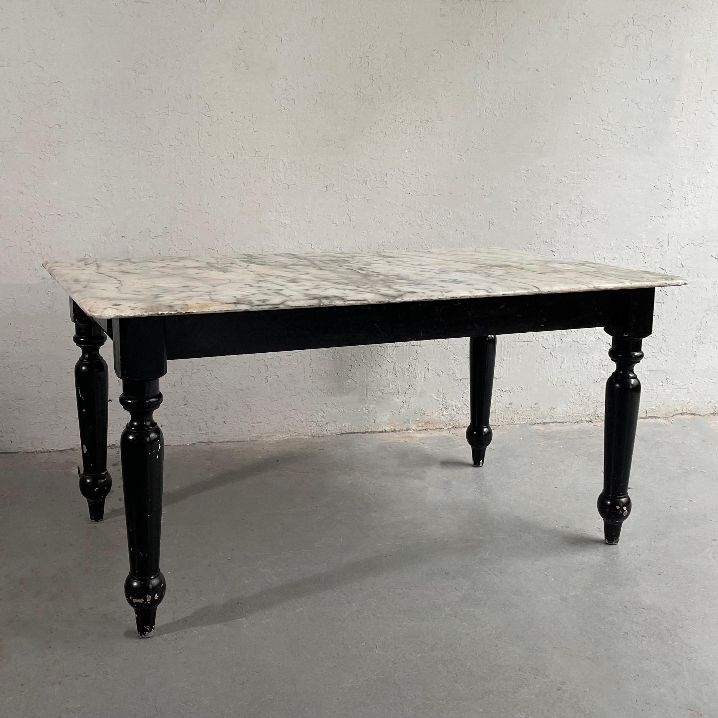 Handsome, industrial, midcentury, library table features a beveled edge, white and gray grain marble top with contrasting, black lacquered, turned maple legs and apron. The table includes two small side drawers on either side of the apron with wood