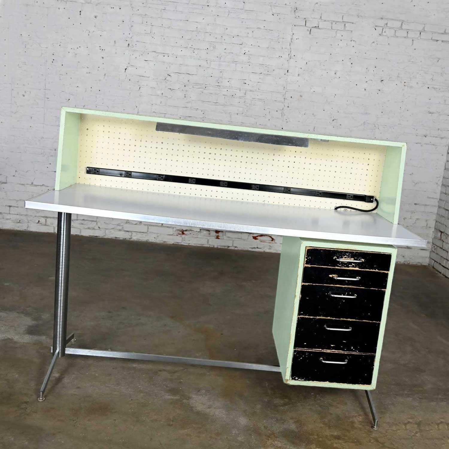 Fabulous industrial Mid-Century Modern distressed stand-up desk or worktable by American Optical Consul Furniture Line. Comprised of a brushed stainless frame and legs, particle board, white laminate tabletop, aluminum edging, peg board, lights, and