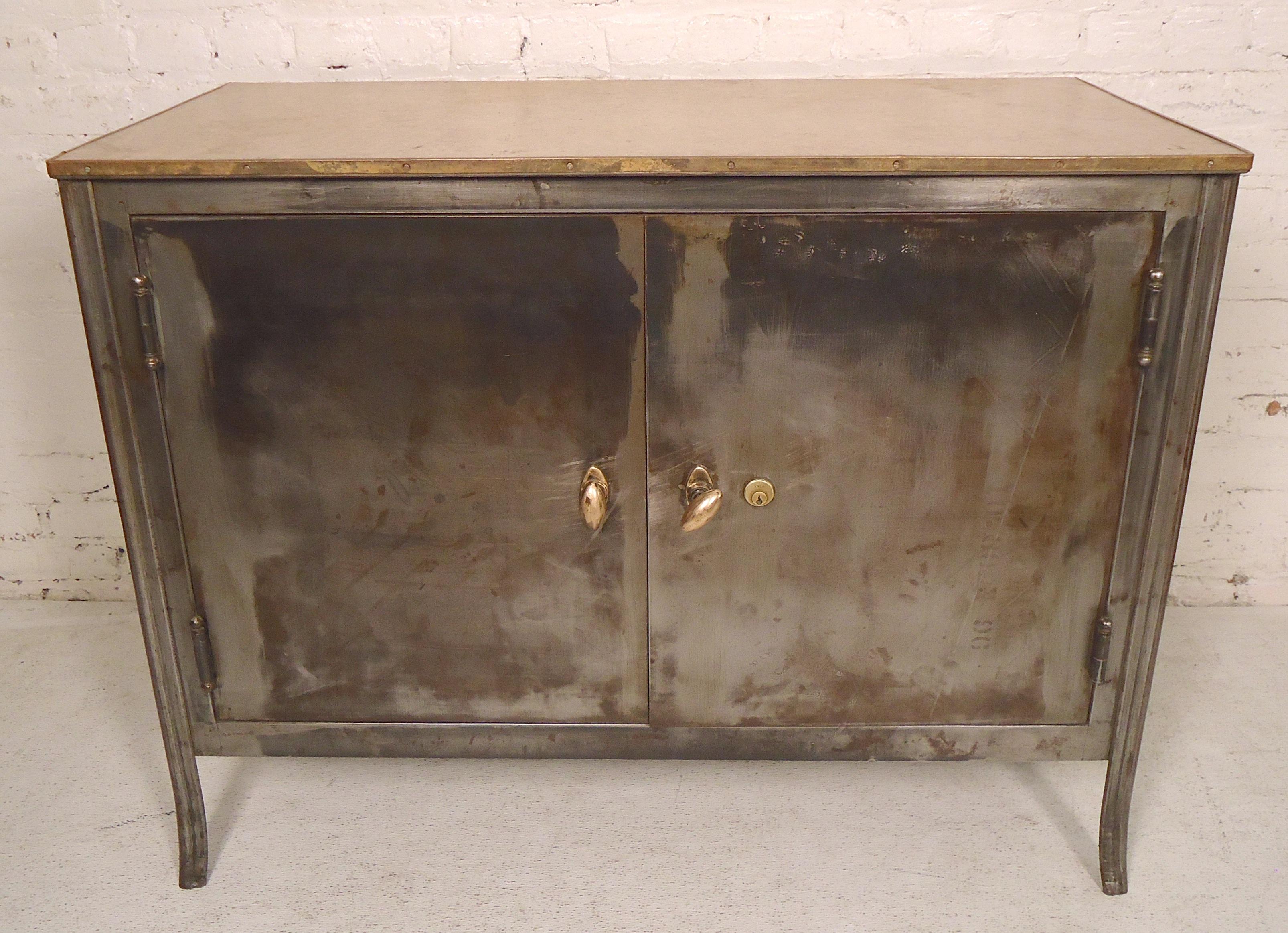 Handsome bare metal style finished two door cabinet with linoleum top. Great machine age style finish and coloring with brass hardware.

(Please confirm item location - NY or NJ - with dealer).
 