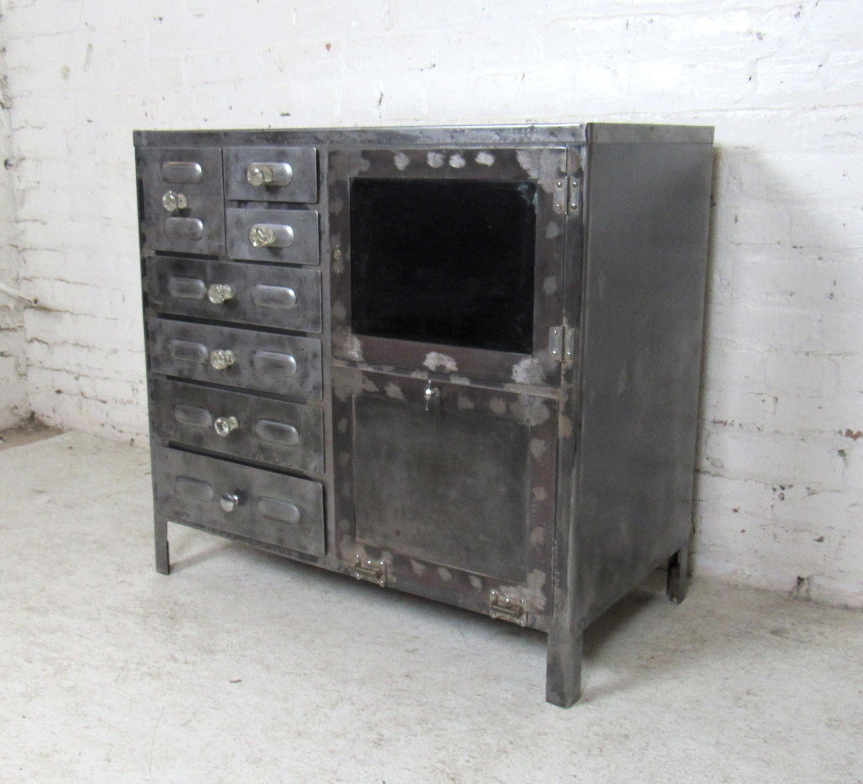 Unique Industrial metal cabinet with ample storage through drawers and larger cabinet doors. Sturdy metal construction is combined with aged character to make this cabinet an eye-catching piece.