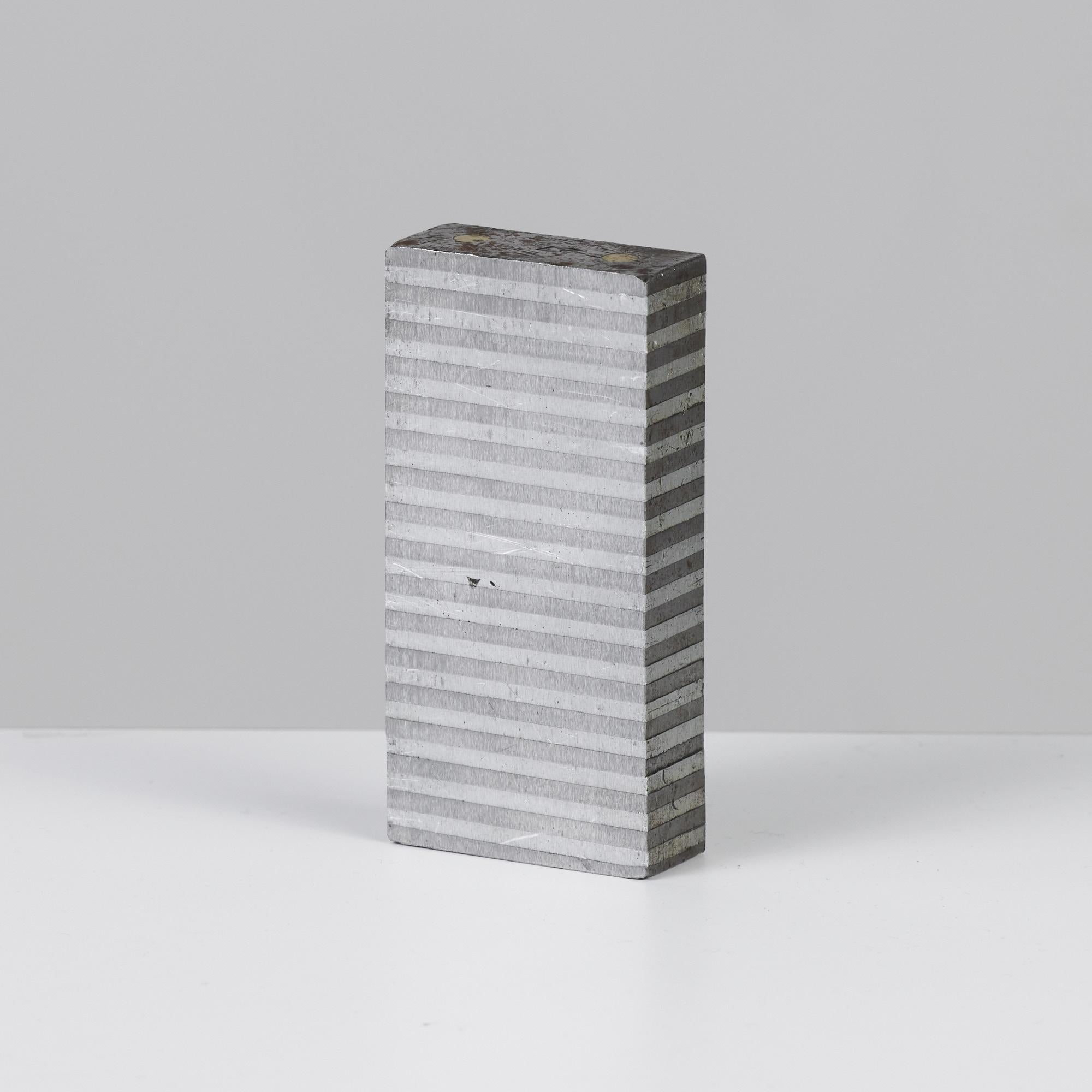 Industrial machine blocks. The brutalist form features alternating striations along the sides with two brass dots on either end. These geometric blocks can be used as bookends or as decorative elements.

Dimensions: 2