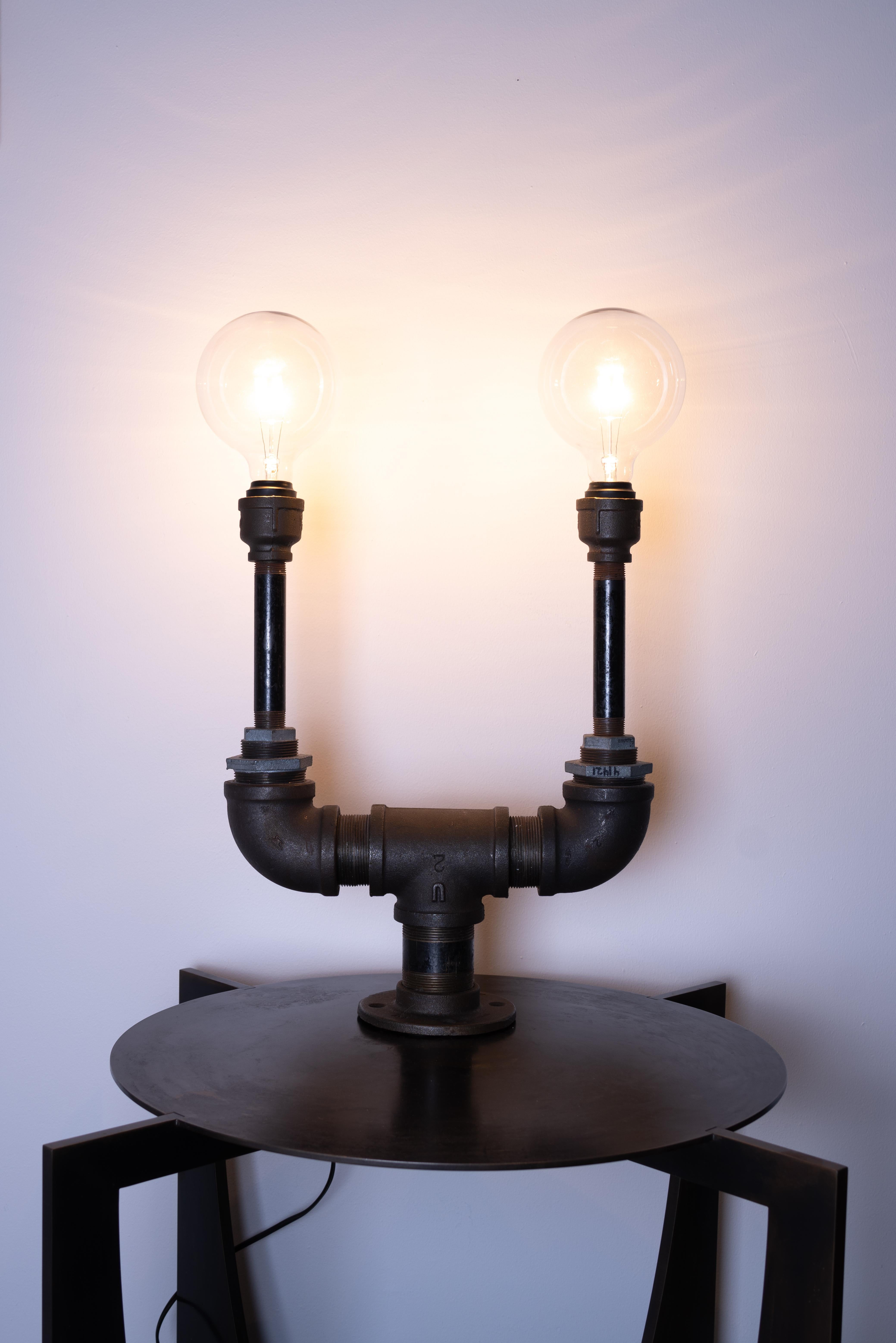 Industrial table lamp by Edelman New York. Made from uniquely sourced, recycled metal piping and fixtures. 

- ) Designed and handmade by Female Founded Design Firm 
- ) Made in the USA
- ) Repurposed materials 
- ) Dimmable Globe Bulb (Not