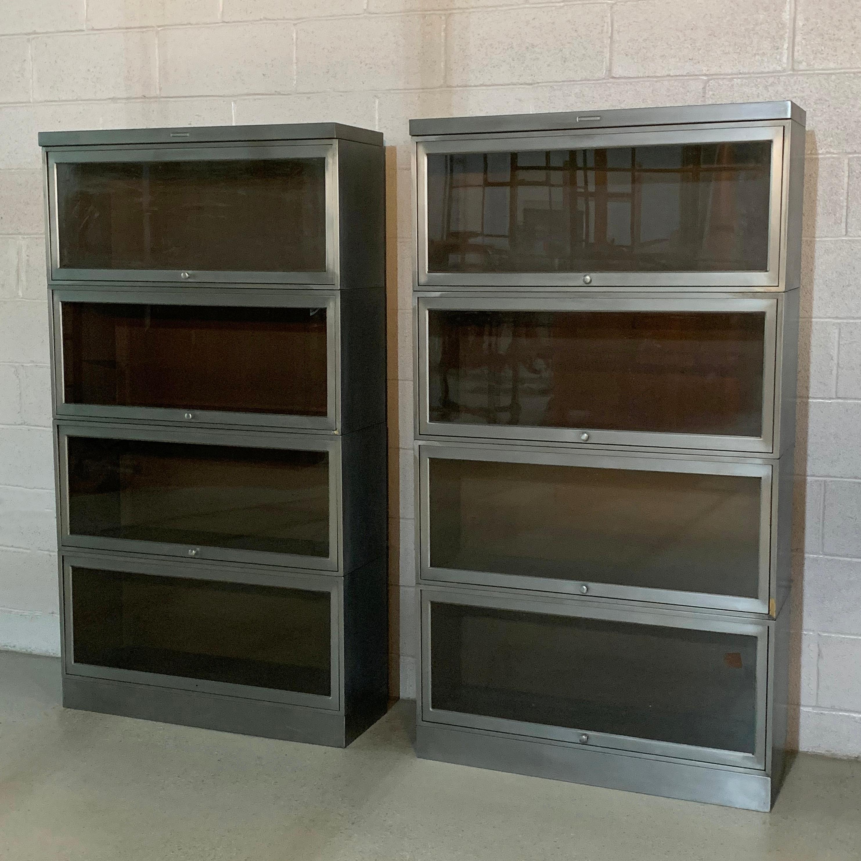 Pair of industrial, midcentury, barrister bookcase cabinets by Steelcase feature 4 stackable, interlocking cases with sliding, glass front doors. The case interiors measure 12.5 inch height x 10.25 inch deep each.