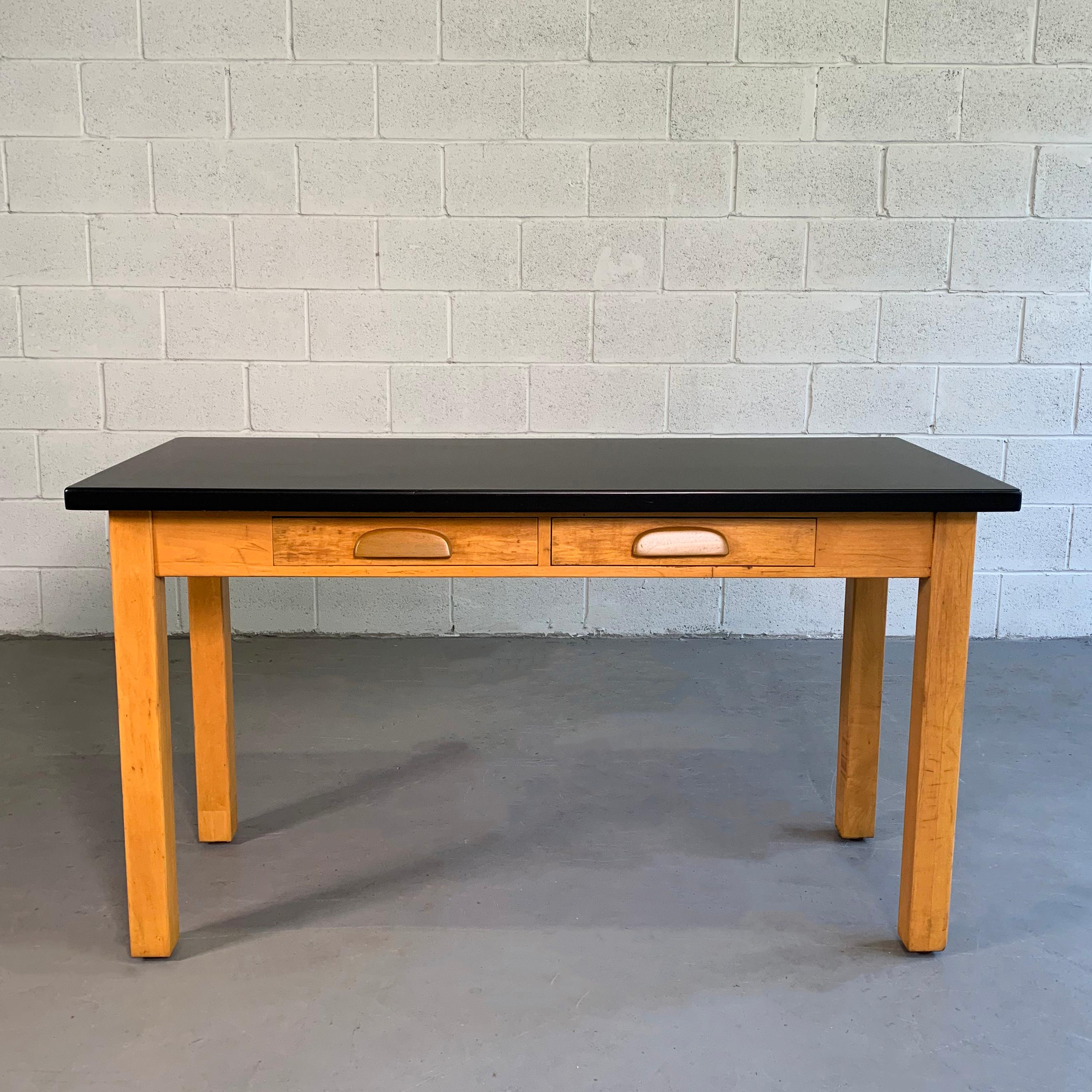 Midcentury, industrial, laboratory table features a 2 drawer, maple base with black, acid-resistant composite top for experiments. At 30.5 inches height, this work table makes a great desk, console, media table or slender dining table. The leg room
