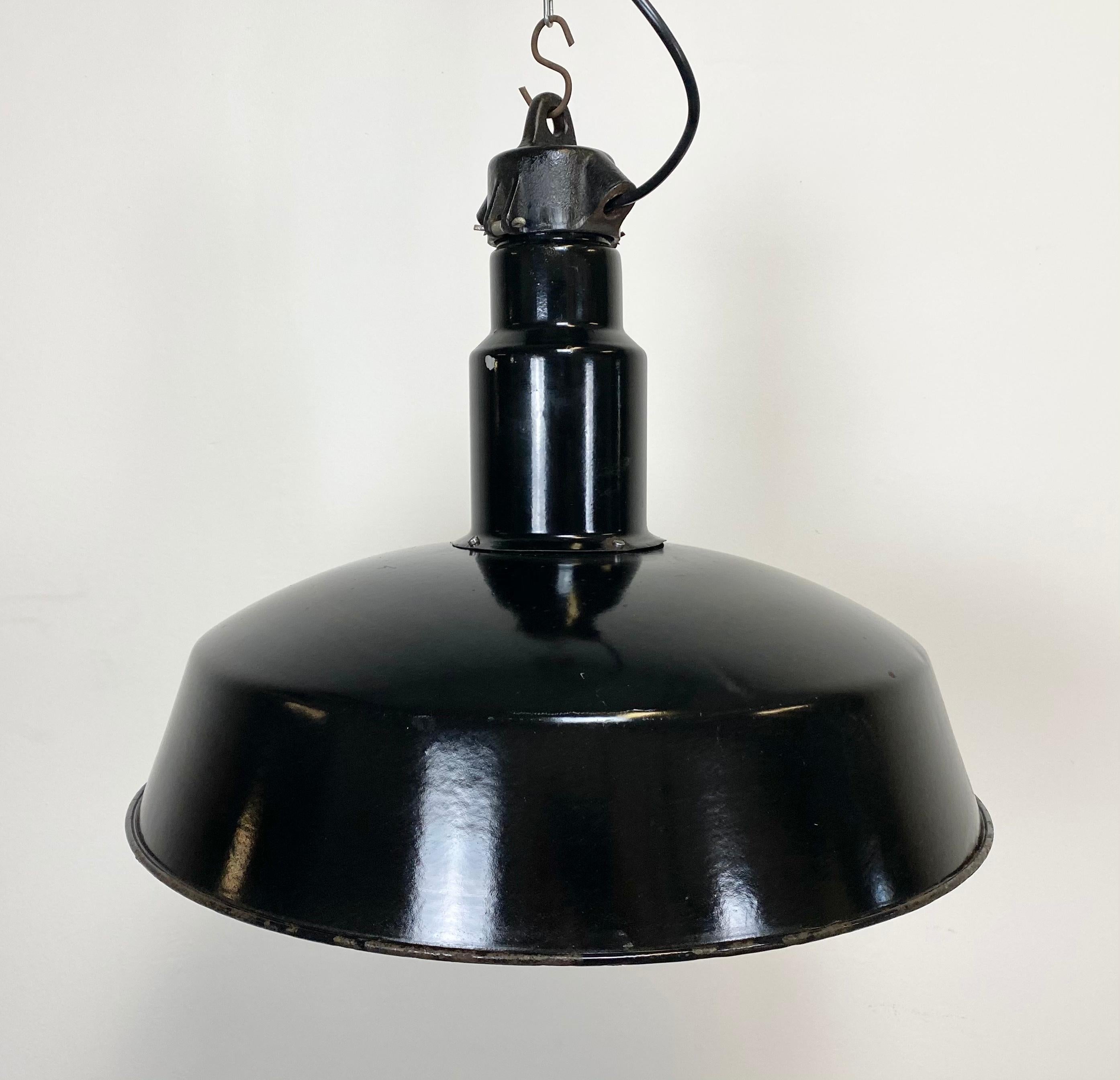 This industrial lamp was made in former Czechoslovakia during the 1950s. It features black enamel exterior , white interior. Cast iron top.New porcelain socket for E 27 lightbulbs and wire. Weight: 4 kg.