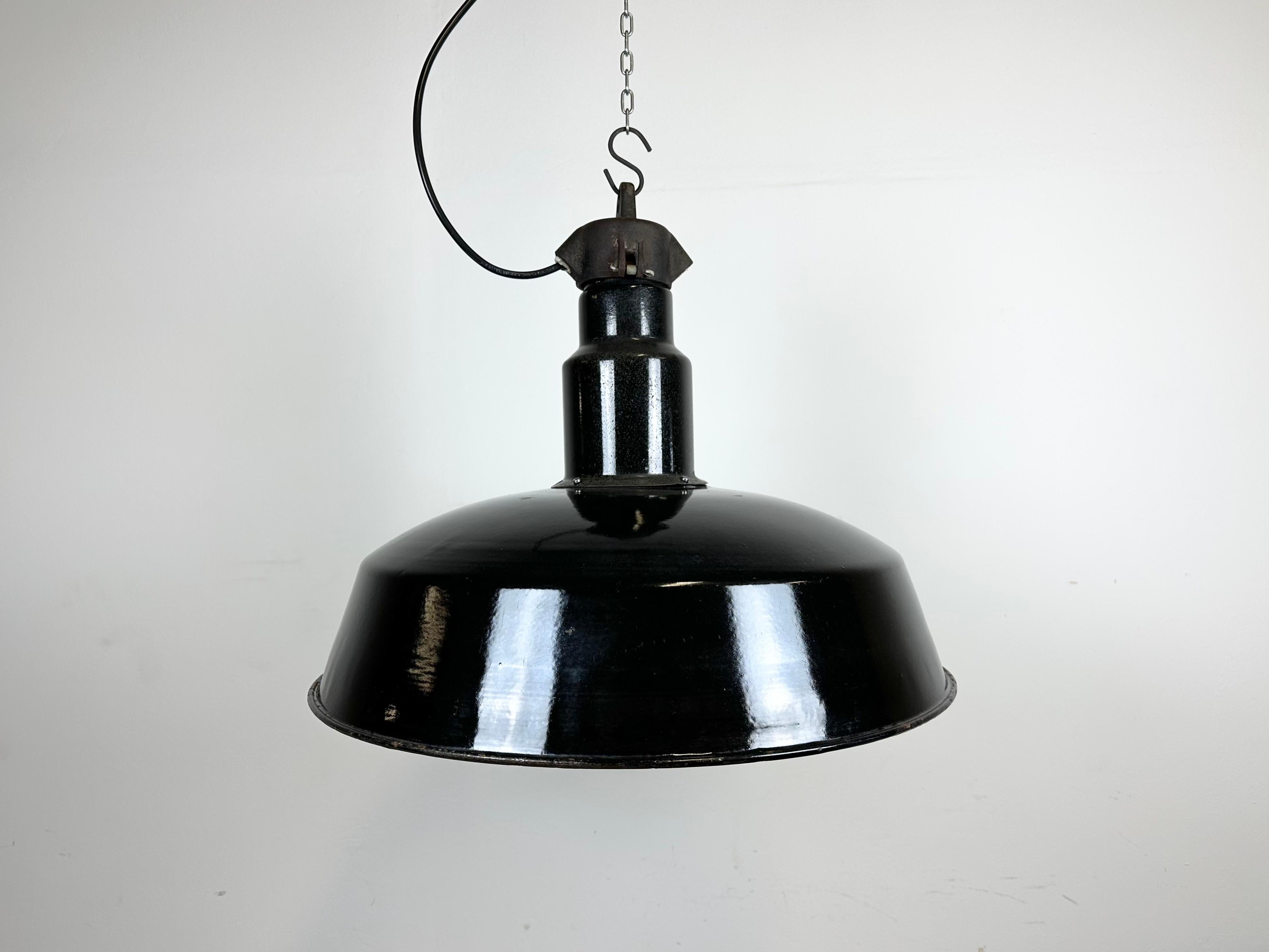 This industrial factory pendant lamp was made in former Czechoslovakia during the 1950s. It features a black enamel exterior ,a white enamel interior and cast iron top.The porcelain socket requires E 27/E 26 light bulbs . New wire. The weight of the