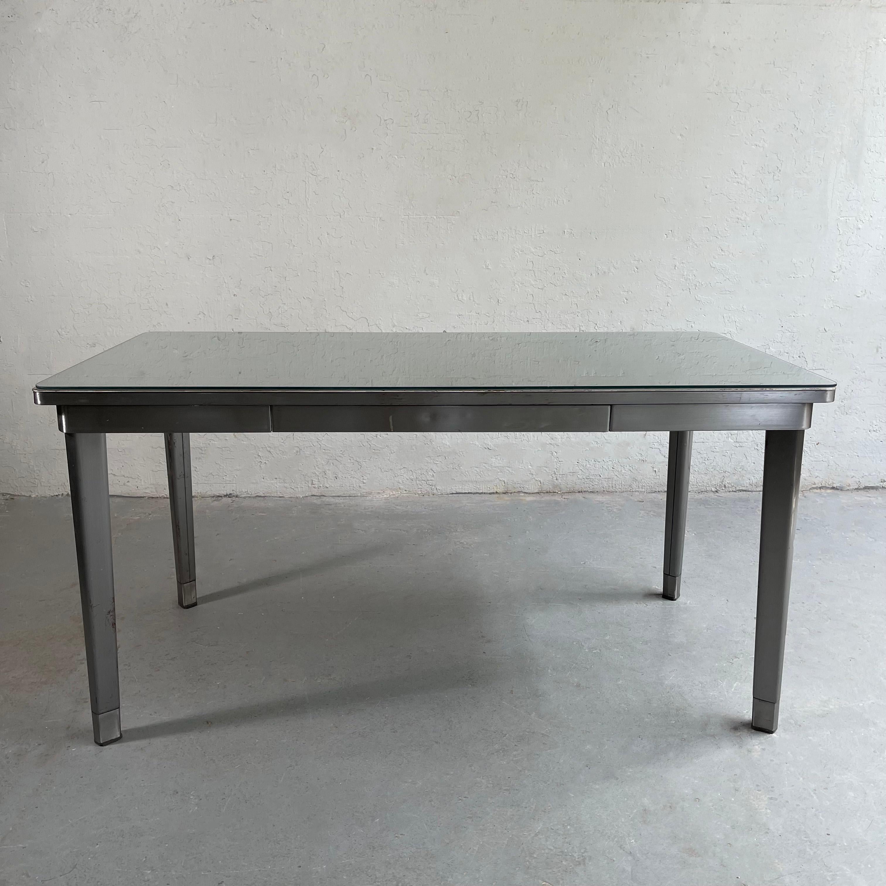 Midcentury, Industrial, brushed steel, police station desk features one center drawer and a removeable glass top. This minimal desk can do double duty as a great work station or Industrial dining table. The apron of the table is 27 inches height.
