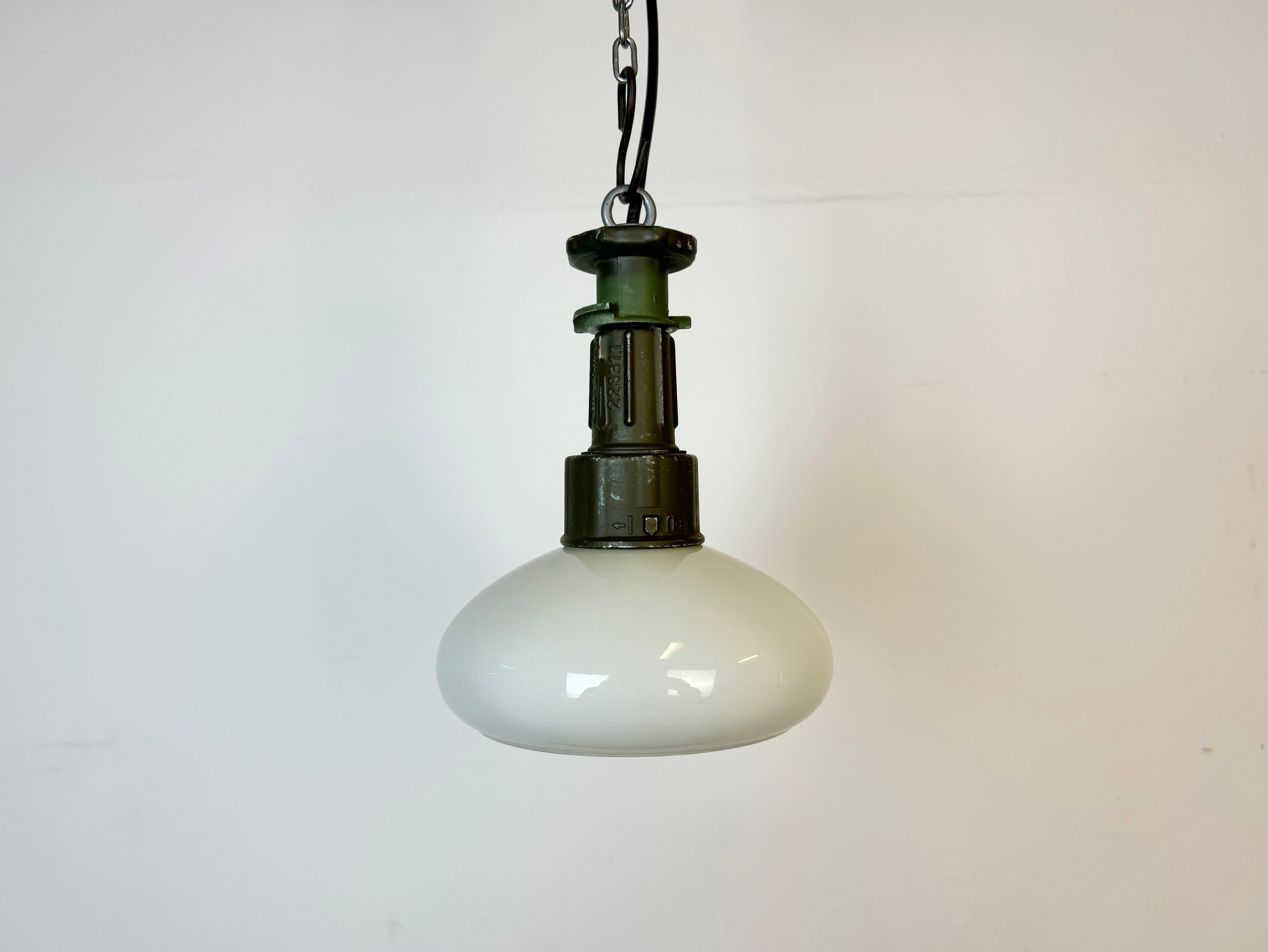 Industrial army pendant light made in Poland during the 1960s.It features green cast aluminium top and a milk glass shade. The socket requires standard E 27/ E26 light bulbs. New wire. The weight of the lamp is 1 kg. The diameter of the shade is 18