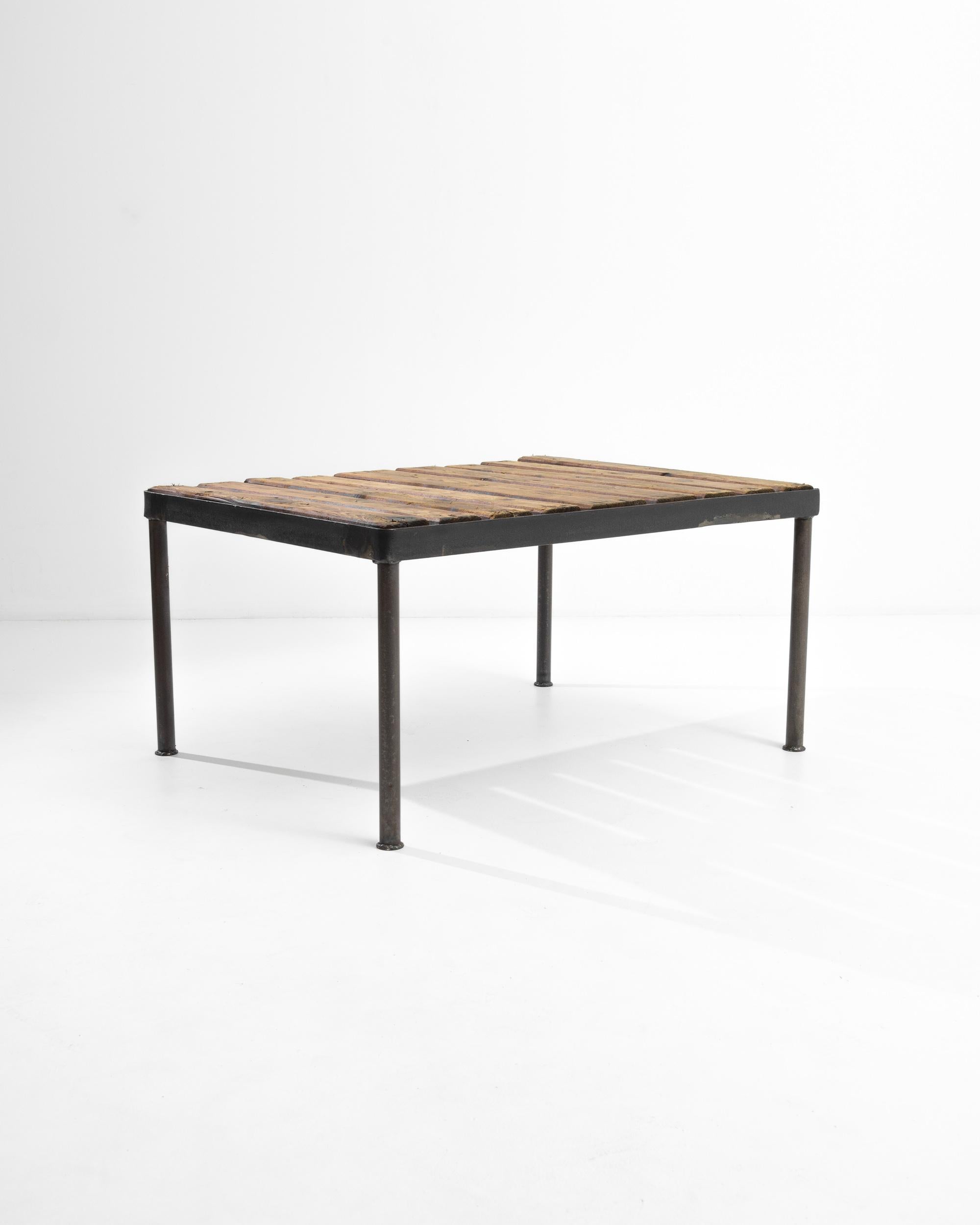 The uncluttered simplicity of this 20th Century French coffee table makes it adaptable for a wide variety of spaces and styles. The wrought iron frame lends the design an industrial inflection, while the organic wooden slats of the tabletop add a