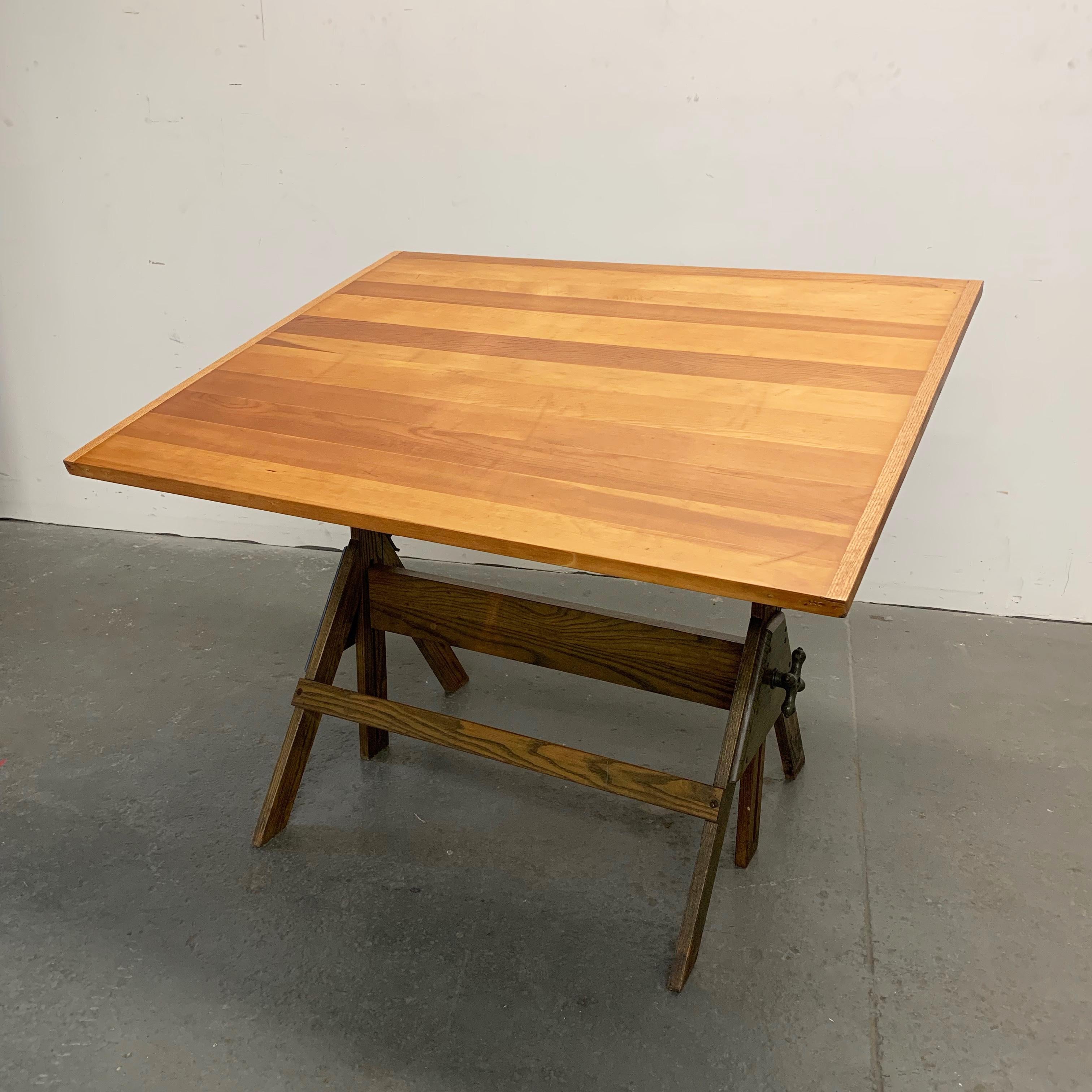 Industrial, mid-20th century, drafting table features an oak base with cast iron fittings and douglas fir top. The table is height adjustable from 32 - 42 inches and tilt adjustable on both sides. The foot print is 32 wide inches x 29 inches deep.
