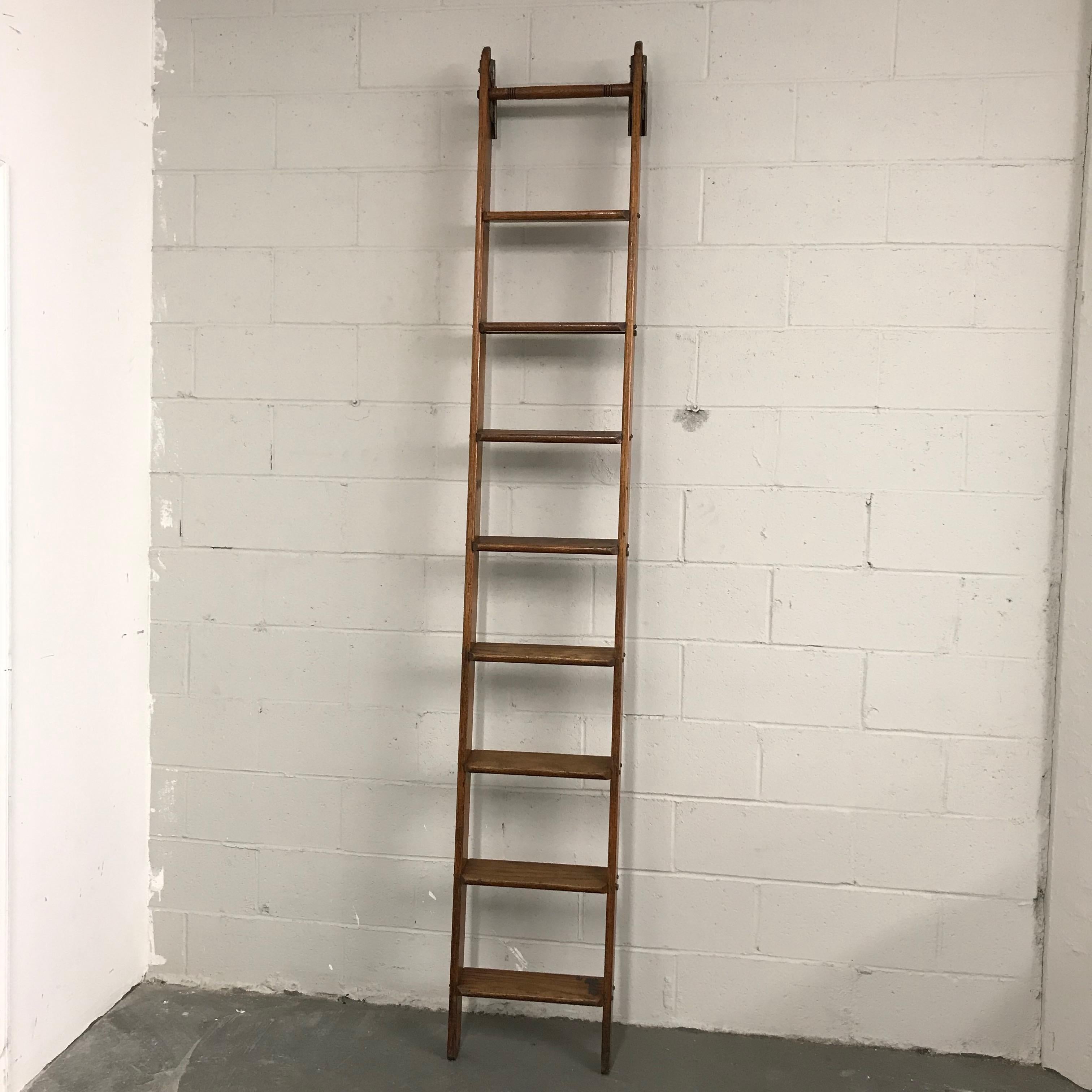 Industrial, oak library ladder by Putnam features decorative steel hooks at the top. The rungs are 4 inches wide.