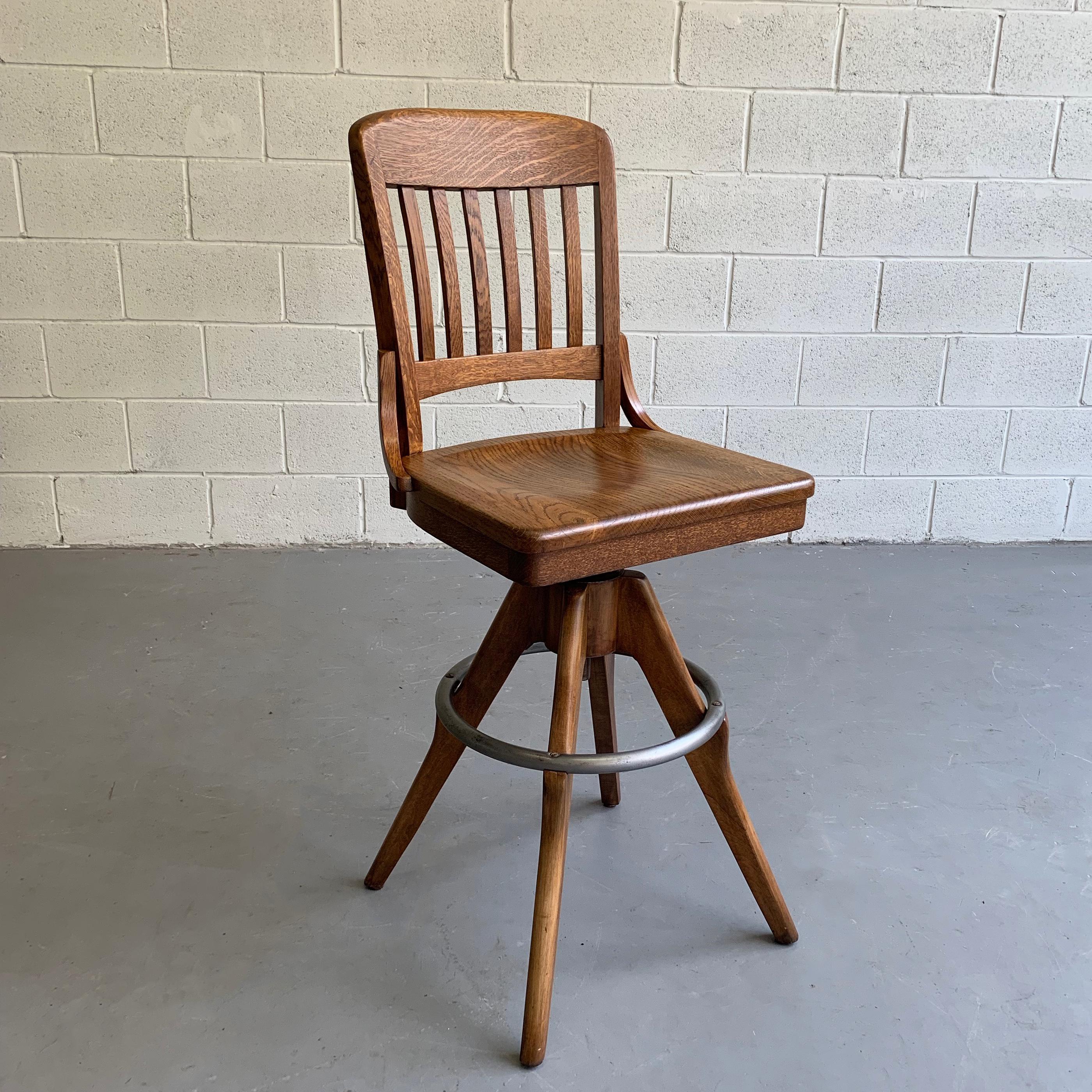 Handsome, industrial, oak drafting stool by Gunlocke features a swivel, seat that is height adjustable from 28-31 inches and a steel ring footrest. The seat measures 18.5 inches wide x 16 inches deep, the foot print is 26 inches diameter.
