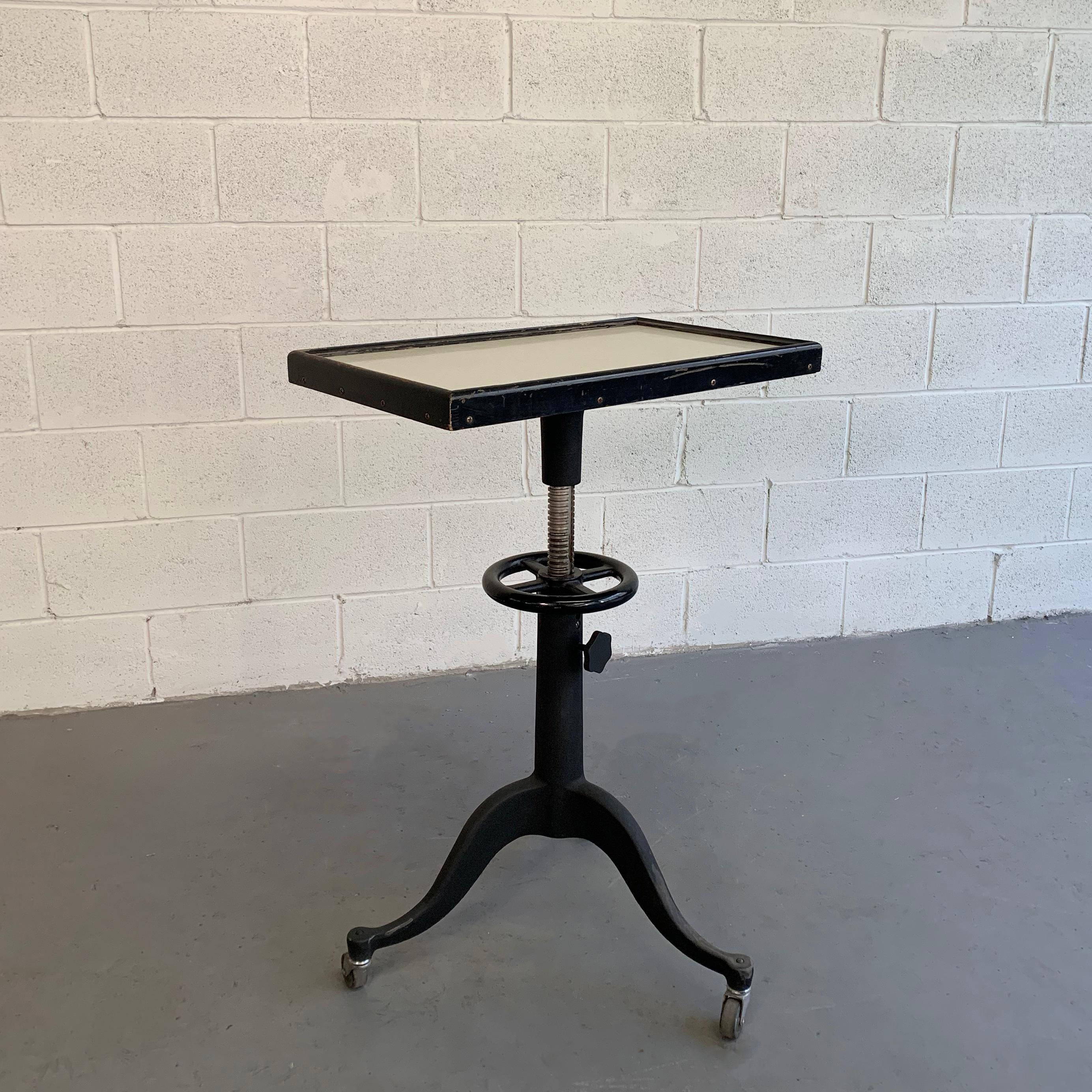Industrial, optometry examination, table by Bausch & Lomb features a formica top in a wood frame atop a pedestal, cast iron and steel base that is height-adjustable from 31 - 36 inches.
