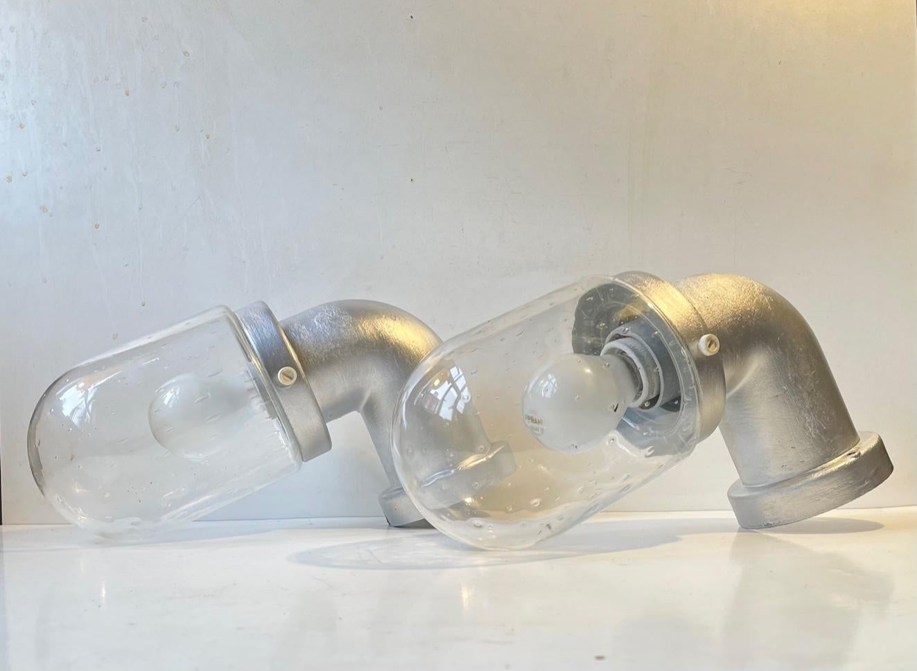 Matching pair of outdoor wall lights made from lacquered plastic and. clear glass with controlled air bubbles. Their pipe shape gives them a distinct industrial look. The set features original porcelain sockets with a capacity up to 100 watts E27.
