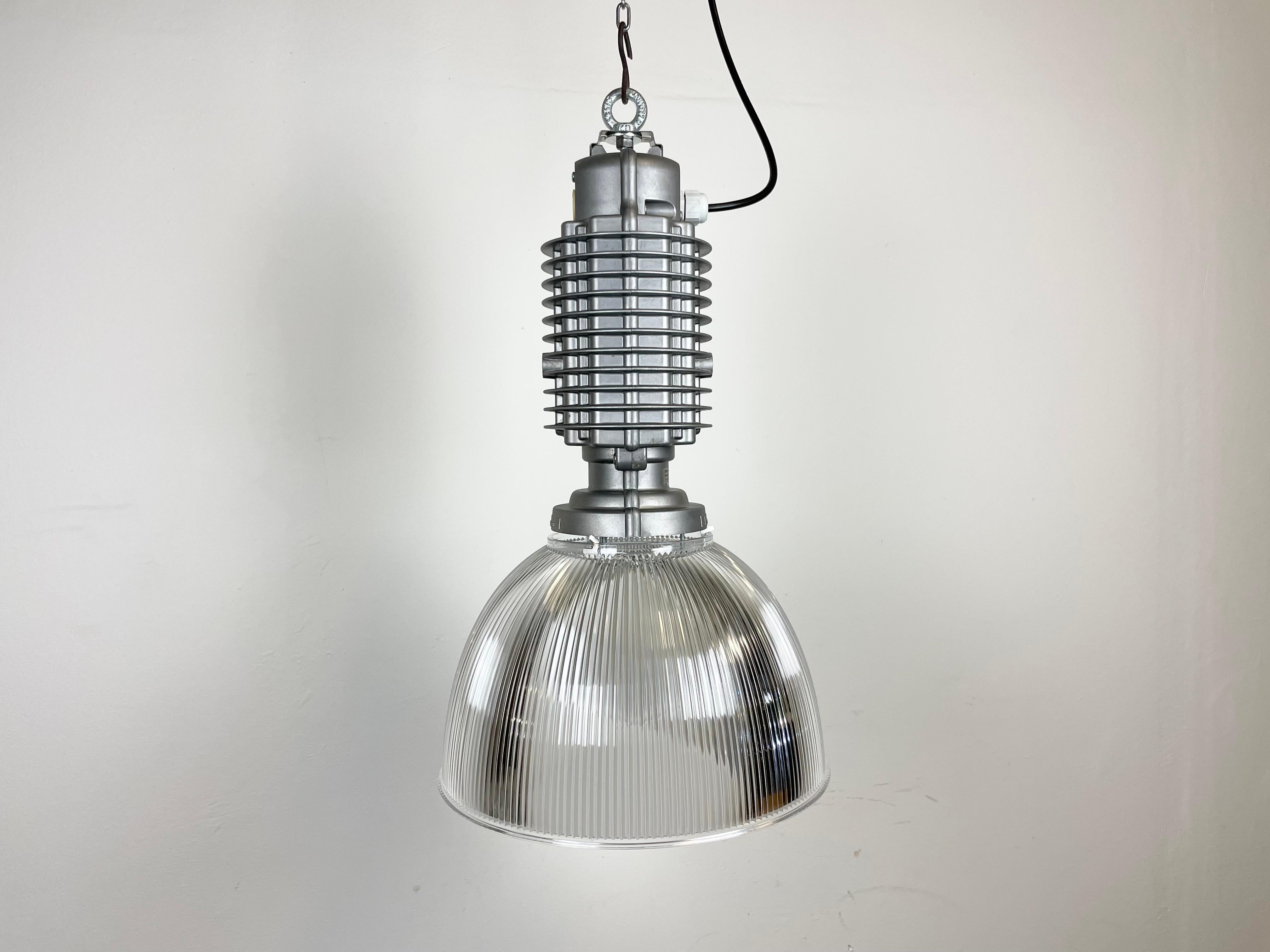 This industrial pendant lamp was designed by Charles Keller for Zumtobel Staff during the 1990s. It features a cast aluminum top and a transparent plastic shade. The original socket requires E27 lightbulbs. New wire. The diameter of the shade is 32