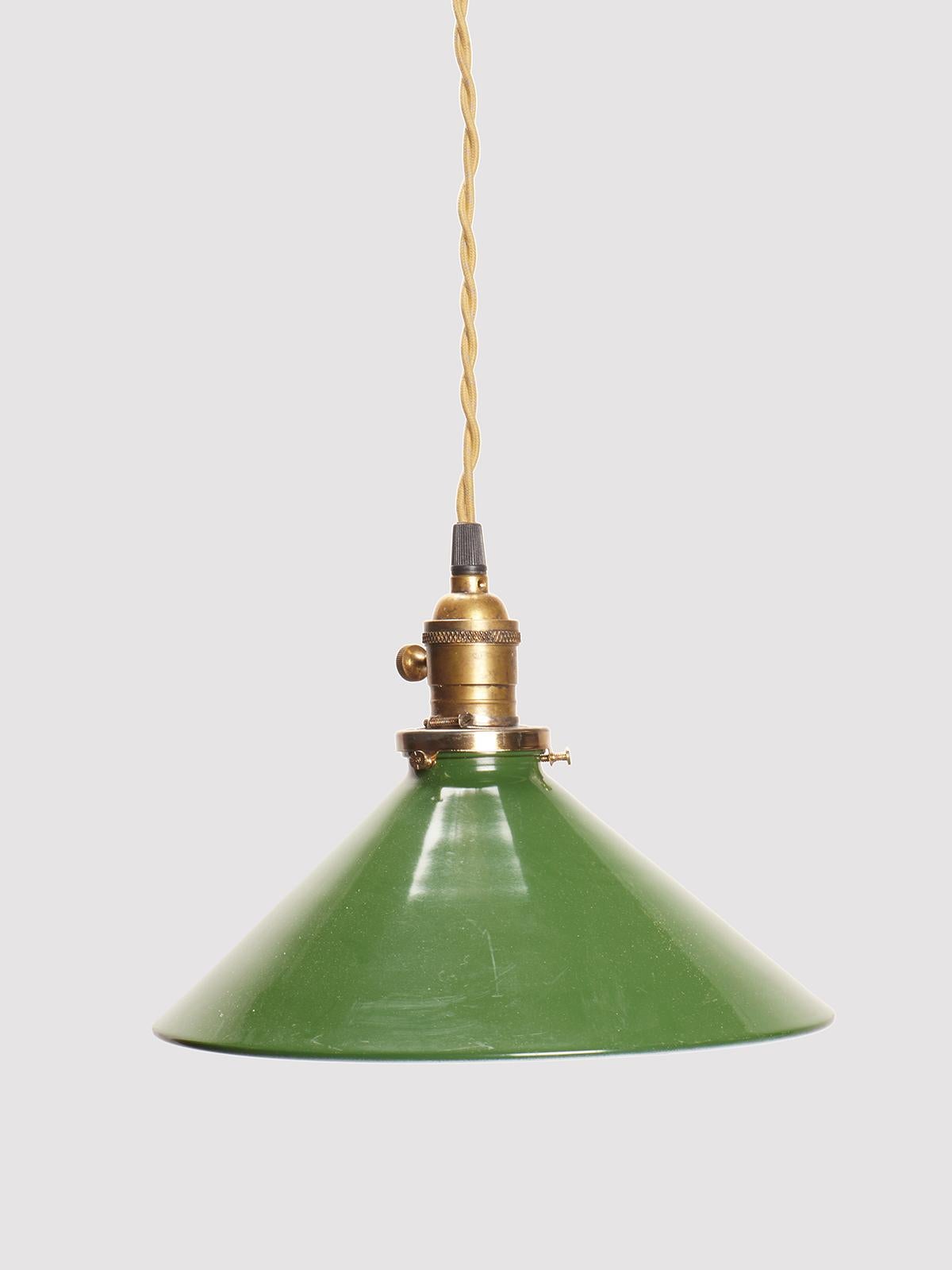Industrial swinging lamp, from a tailor's shop, made of a circular cone, in green enameled metal, where on the inside, are positioned mirror trapeziums to refract the light, with brass bulb attachment. Woven wire covered in fabric. United States of