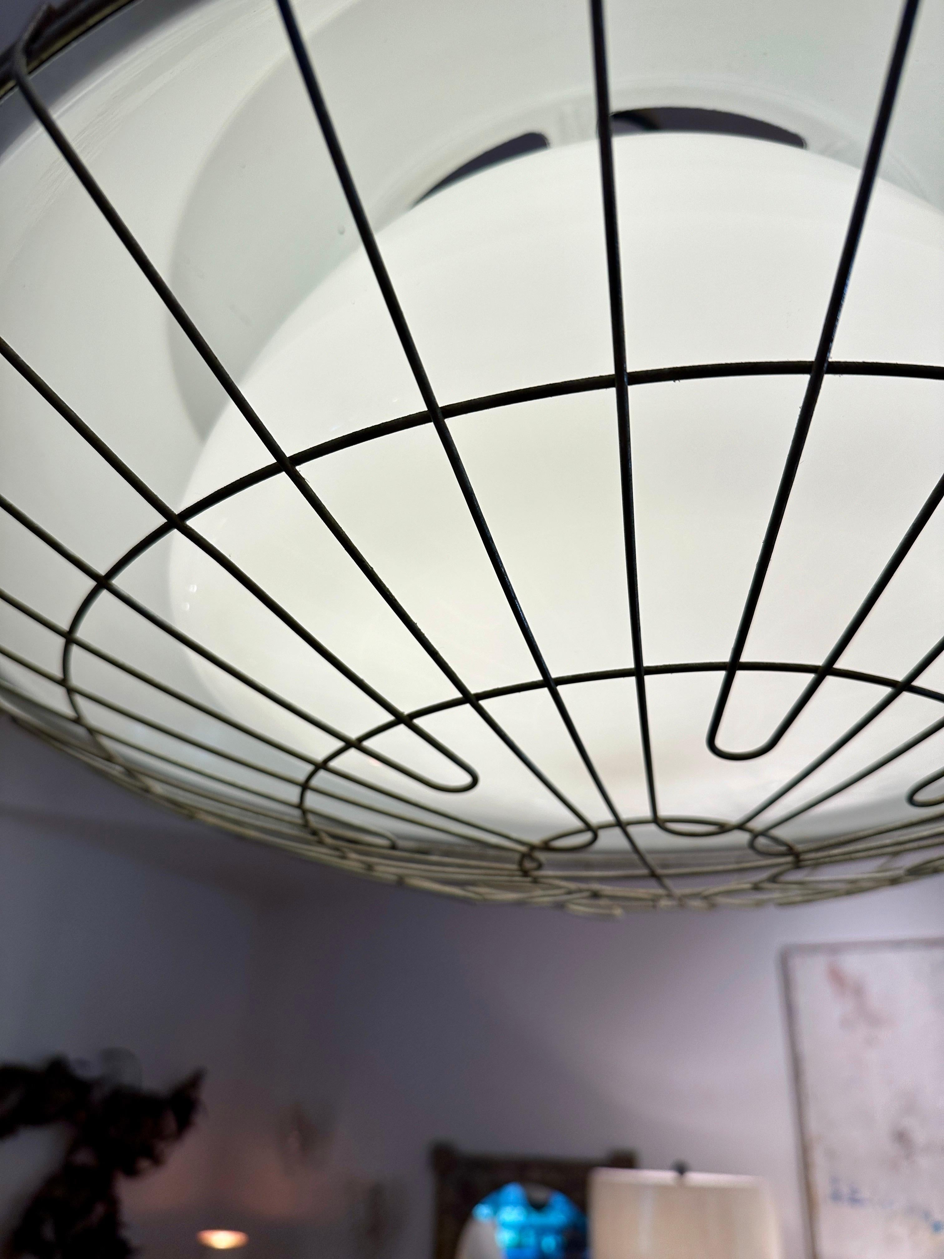 This industrial pendant light features the original milk glass diffuser to interior, surrounded by a white enamel shell and galvanized metal cage.  This is such a fun piece and has many possible uses in your design space.