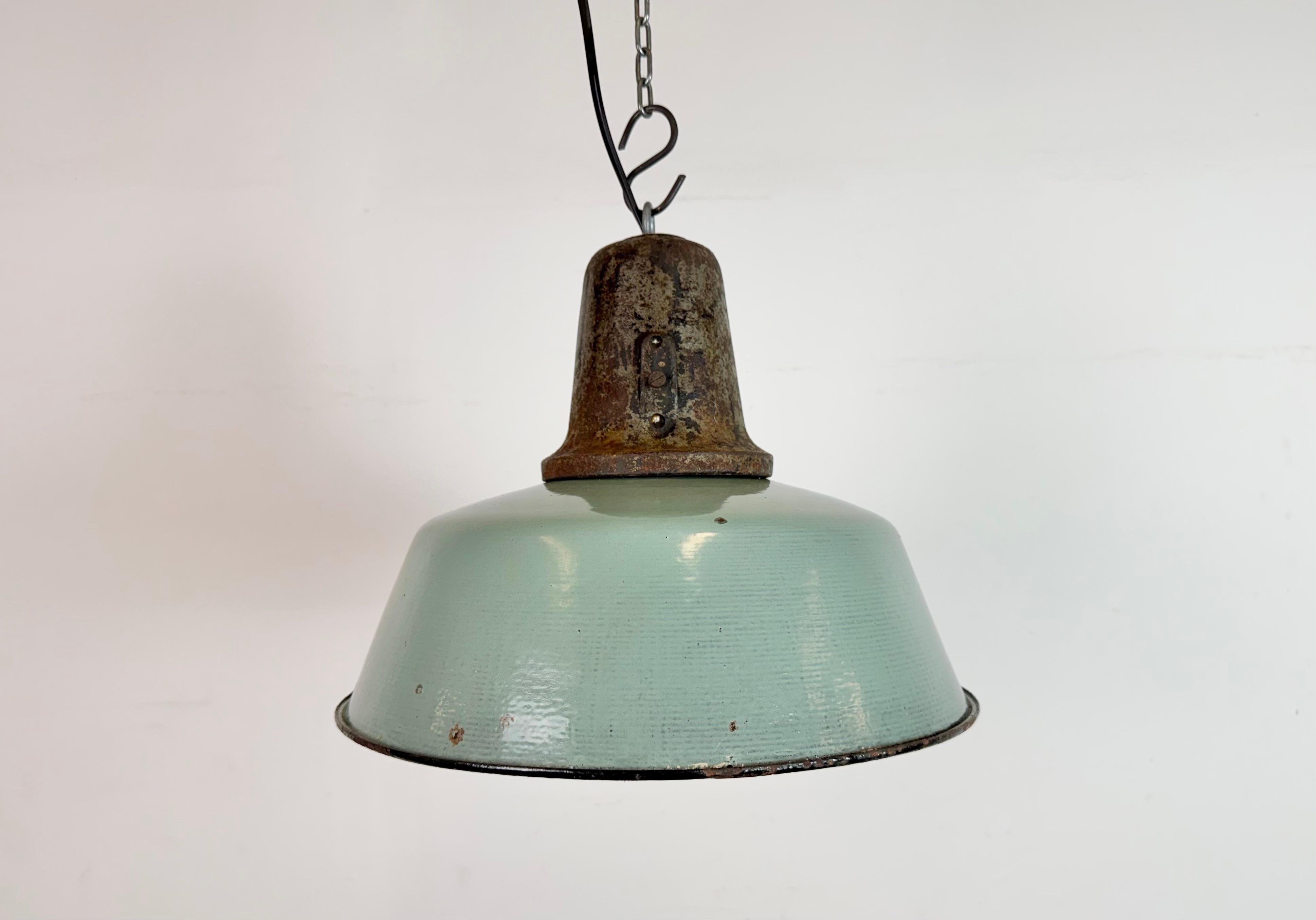Lámpara colgante industrial de esmalte de petróleo fabricada en Polonia en la década de 1960. Esmalte blanco en el interior de la pantalla. Encimera de hierro fundido. El casquillo de porcelana requiere bombillas E 27/ E26. Cable nuevo. Totalmente