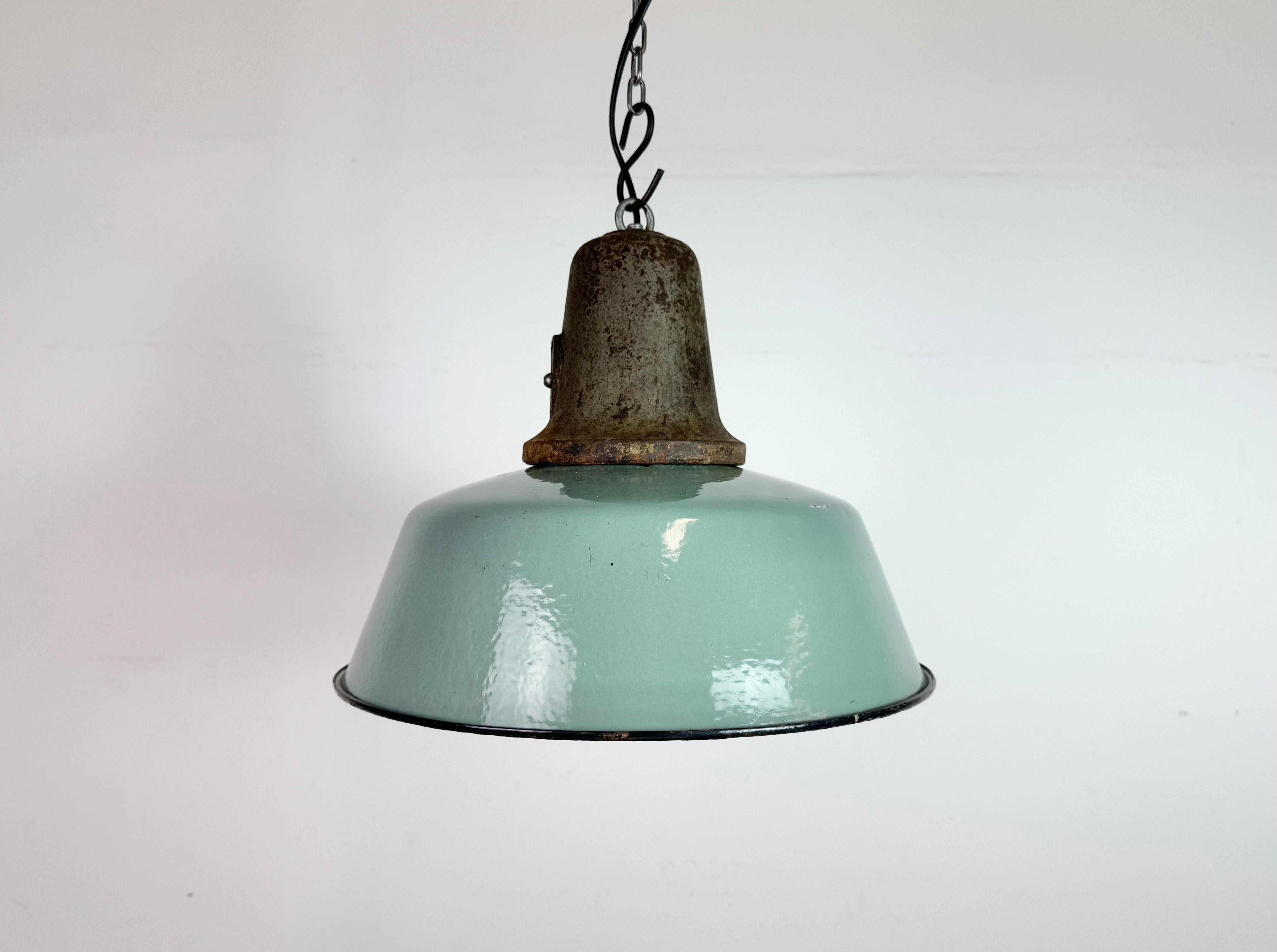 Lampada a sospensione industriale in smalto a petrolio realizzata in Polonia negli anni '60. Smalto bianco all'interno del paralume. Piano in ghisa. L'attacco in porcellana richiede lampadine E 27/ E26. Un nuovo cavo. Completamente funzionante. Il