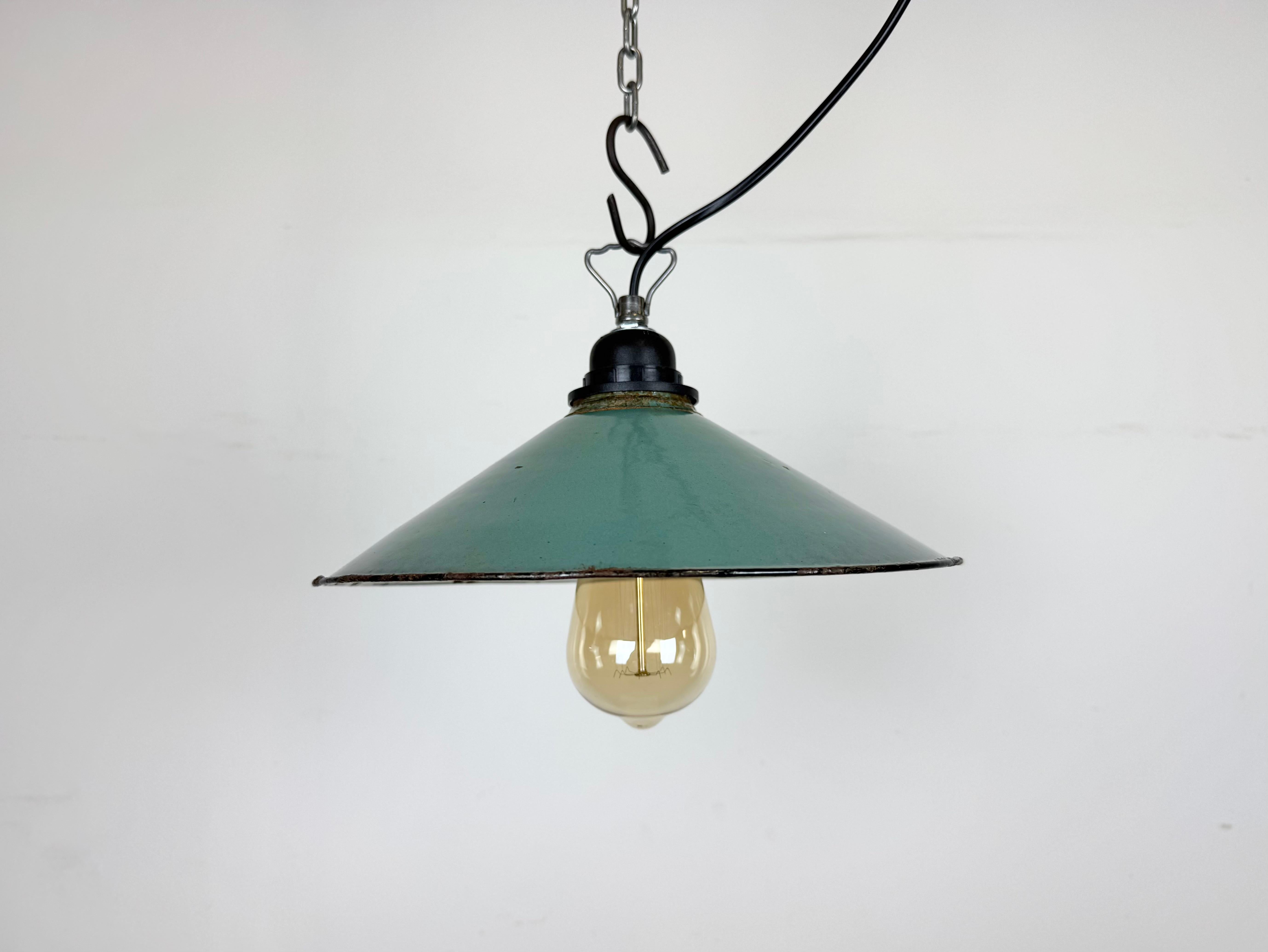 Lampada a sospensione industriale in smalto verde (petrolio) prodotta in Polonia negli anni '60. Smalto bianco all'interno del paralume. La presa in bachelite con gancio in ferro richiede lampadine standard E 27/ E26. Un nuovo cavo. Completamente