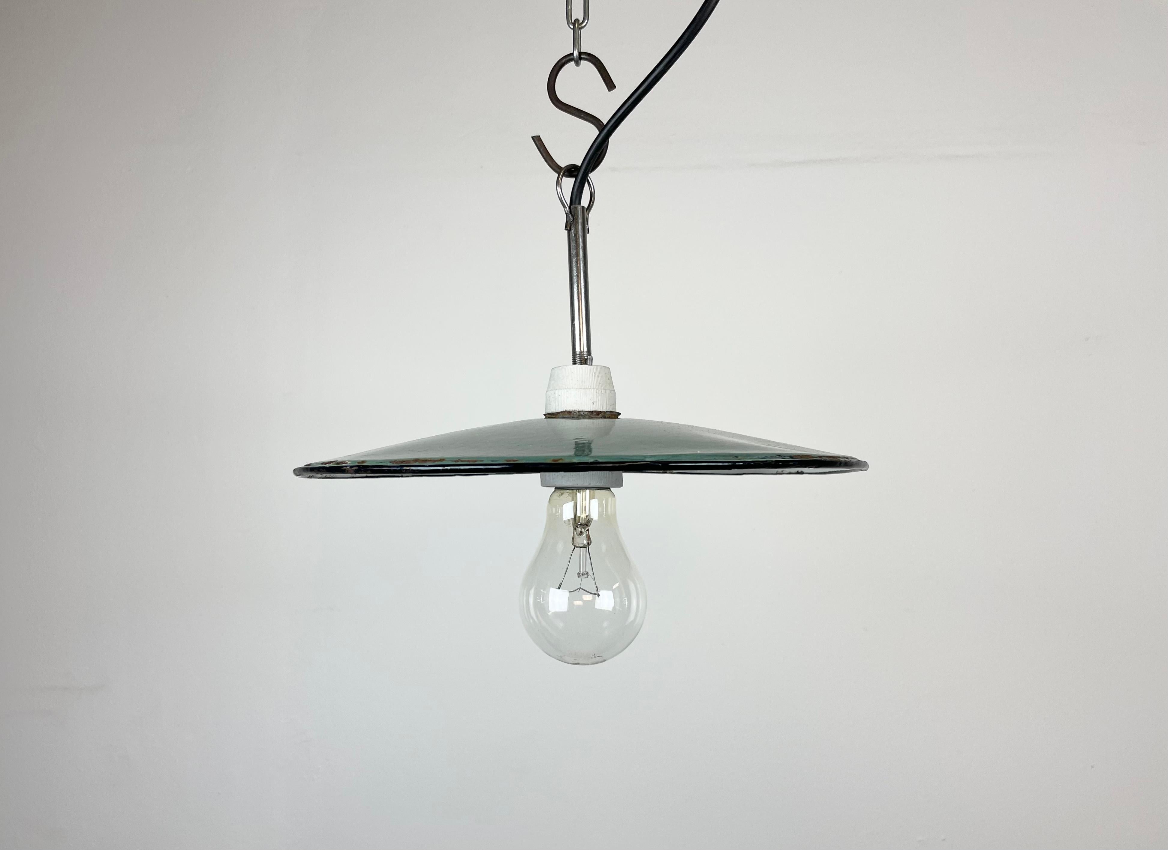 Vintage industrial enamel pendant lamp made in Poland during the 1970s. It features a petrol enamel shade with white enamel interior and iron top. The socket requires E 27 light bulbs. The weight of the lamp is 0,4 kg. New wire.