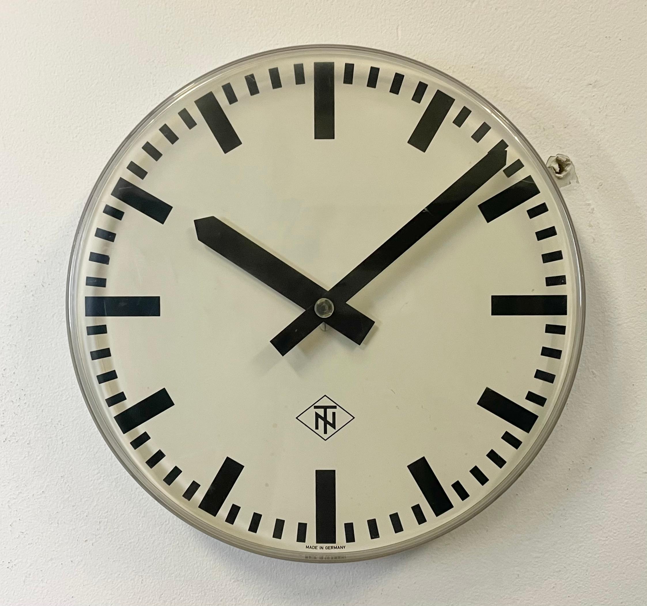 Reloj de pared vintage fabricado por TN Telefonbau und Normalzeit en Alemania durante la década de 1960. Presenta un marco de plexiglás convexo transparente, una esfera de metal blanco y manecillas de aluminio negro. La pieza se ha convertido en un