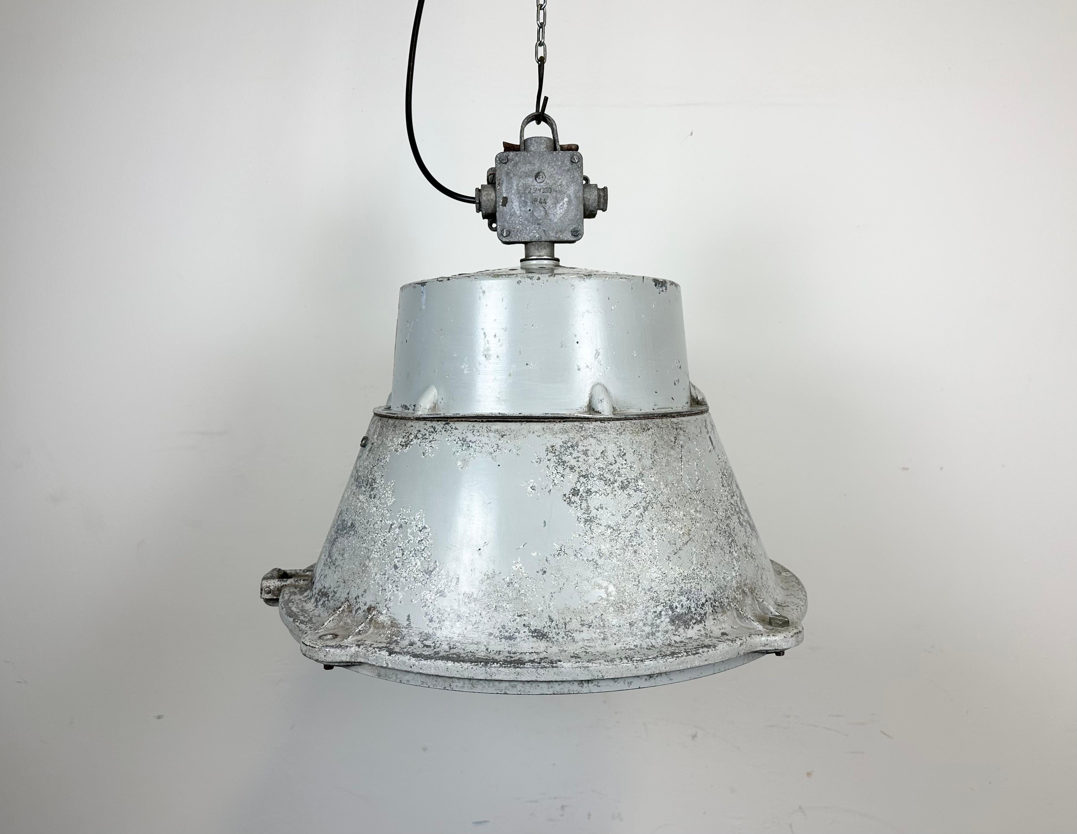 Vintage industrial hanging lamp manufactured in 1970s by MESKO in Skarzysko-Kamienna in Poland. It features a grey cast aluminium body and top. The original porcelain socket E 40 is equipped with an adapter from E40 to E27 and requires E 27/ E 26