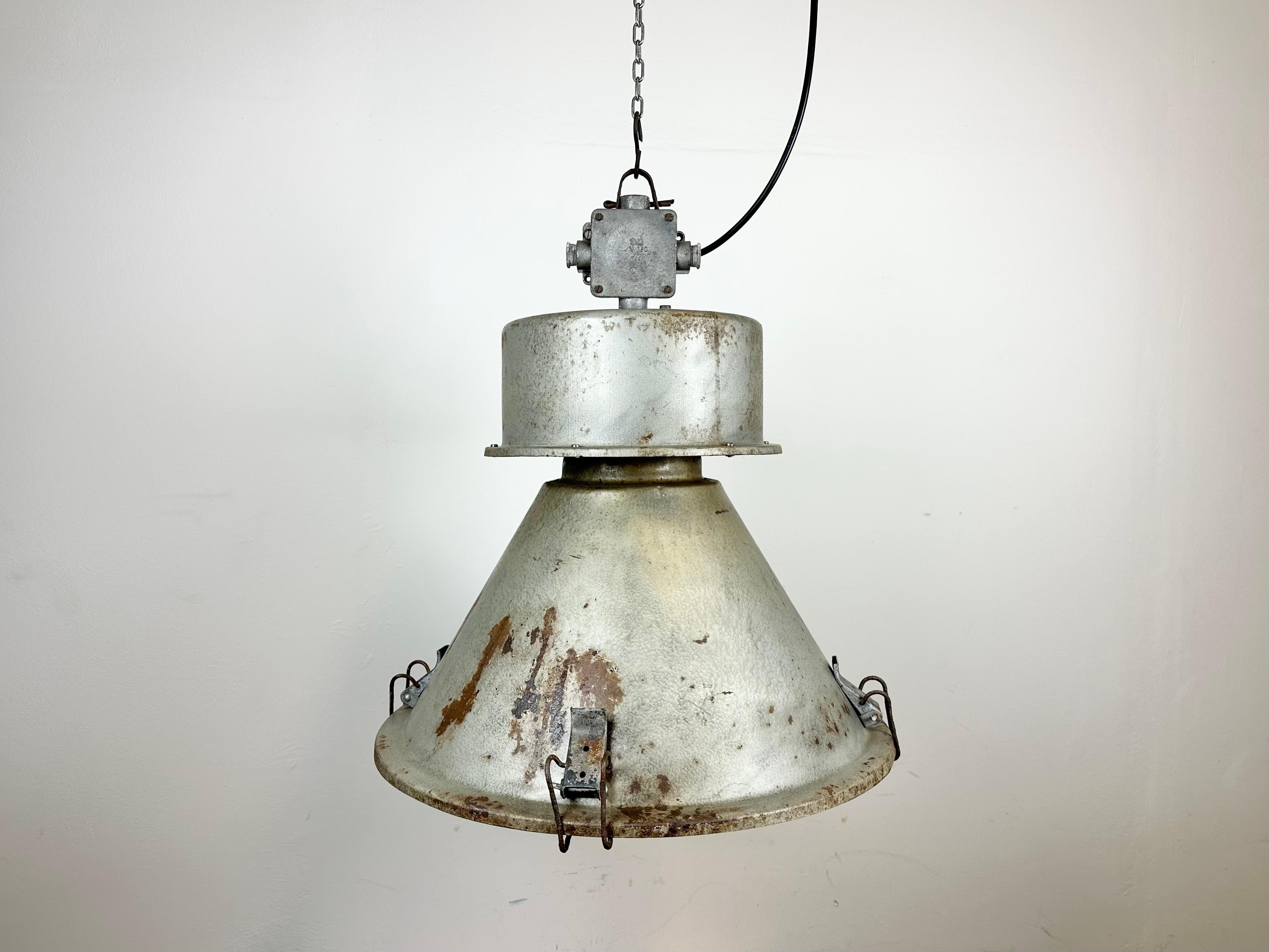 Vintage industrial hanging lamp manufactured in 1970s by MESKO in Skarzysko-Kamienna in Poland. It features a grey iron body and cast aluminium top. The porcelain socket requires E 27/ E26 light bulbs. New wire. The weight of the lamp is 5 kg.