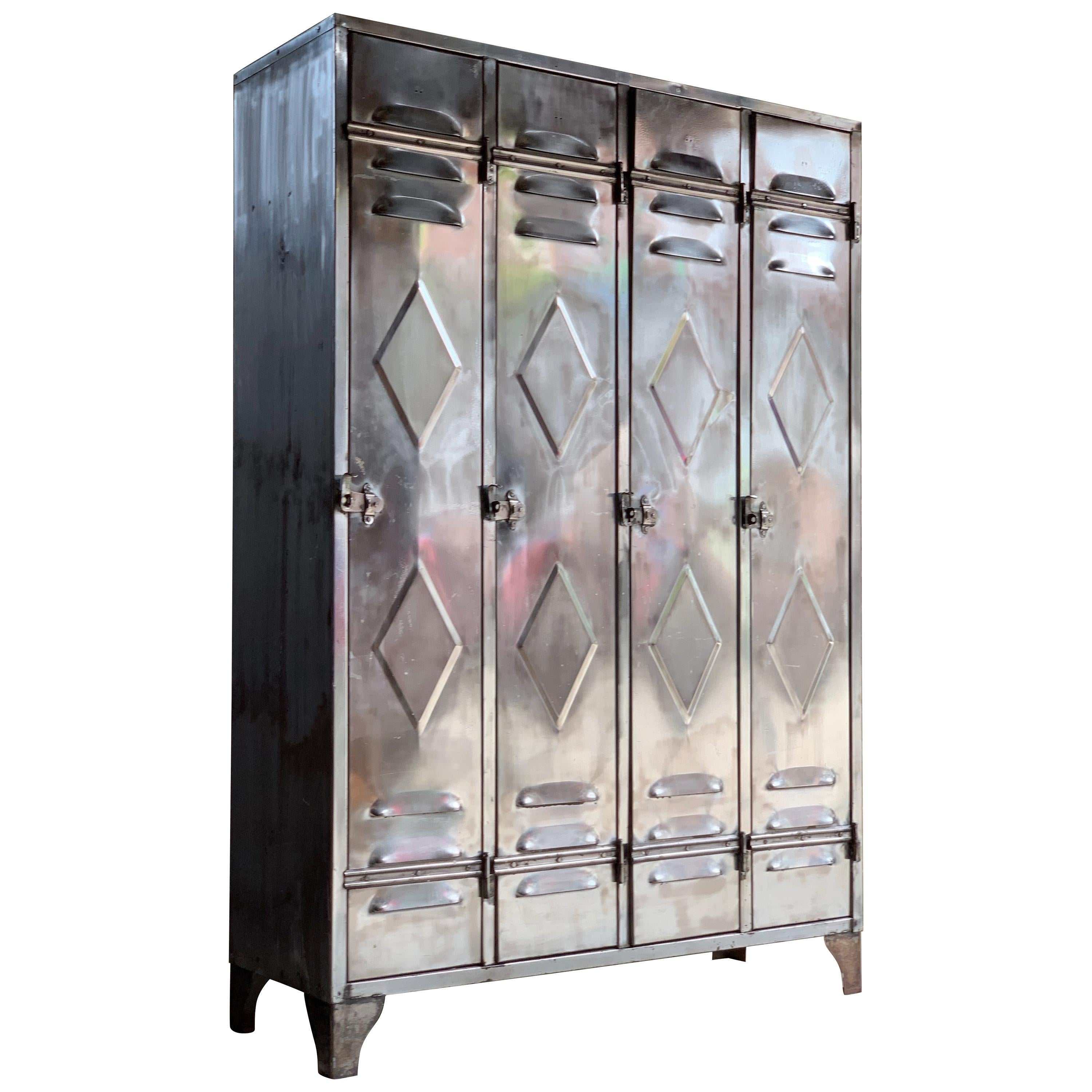 Magnificent mid-20th century industrial polished steel school lockers cabinets circa 1940, with four long double diamond embossed doors with upper and lower vents, each with shelf and two hanging hooks raised on shaped bracket supports, each door