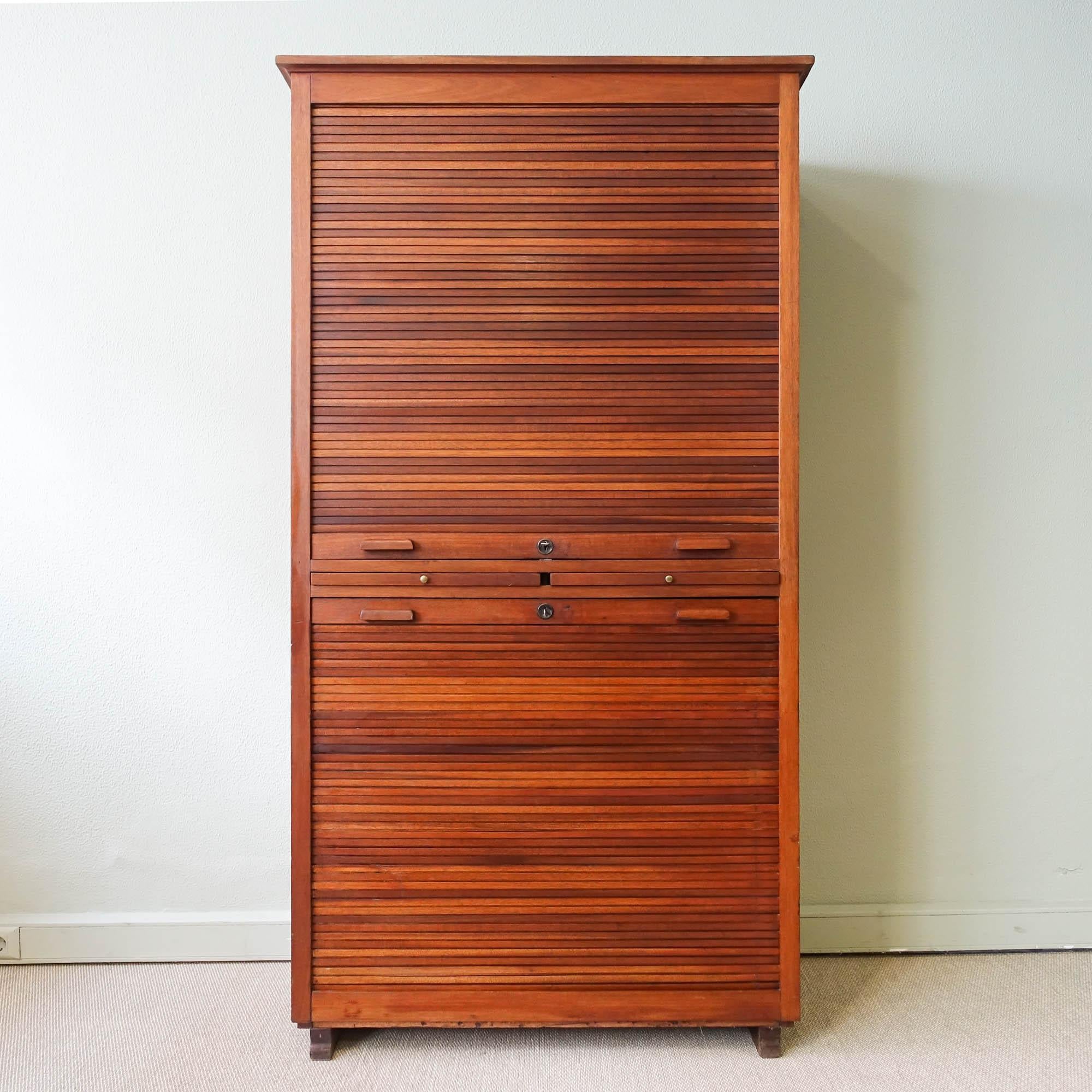 This cabinet was designed and produced by Olaio, in Portugal during 1940's. It is made of oak and has two tambour doors (a pull down from the top and another from the bottom) that conceals 30 drawers, 1 shelf and 2 trays inside. The handles are in