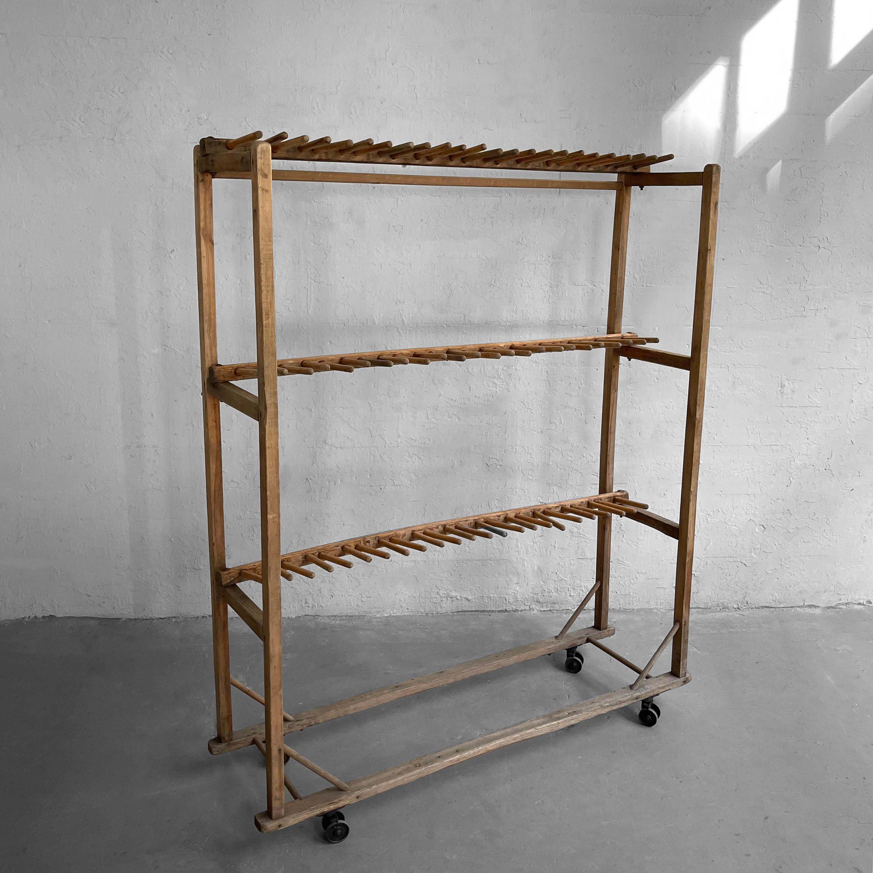 Early 20th century, primitive, industrial, maple, cobbler's shoe rack features three tiers of open, airy, dowls used for shoe drying on casters for rolling. The rack can be re-purpsed for many applications including clothing and wine storage. Two