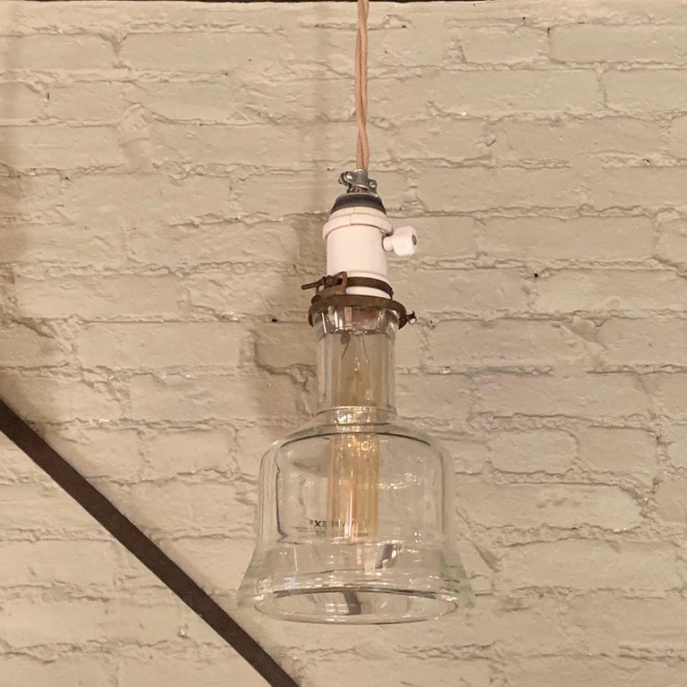 Custom, industrial pendant light features a Pyrex glass shade with brass fitter is newly wired with 36 inches of beige braided cloth cord to accept up to a 150 watt bulb.
