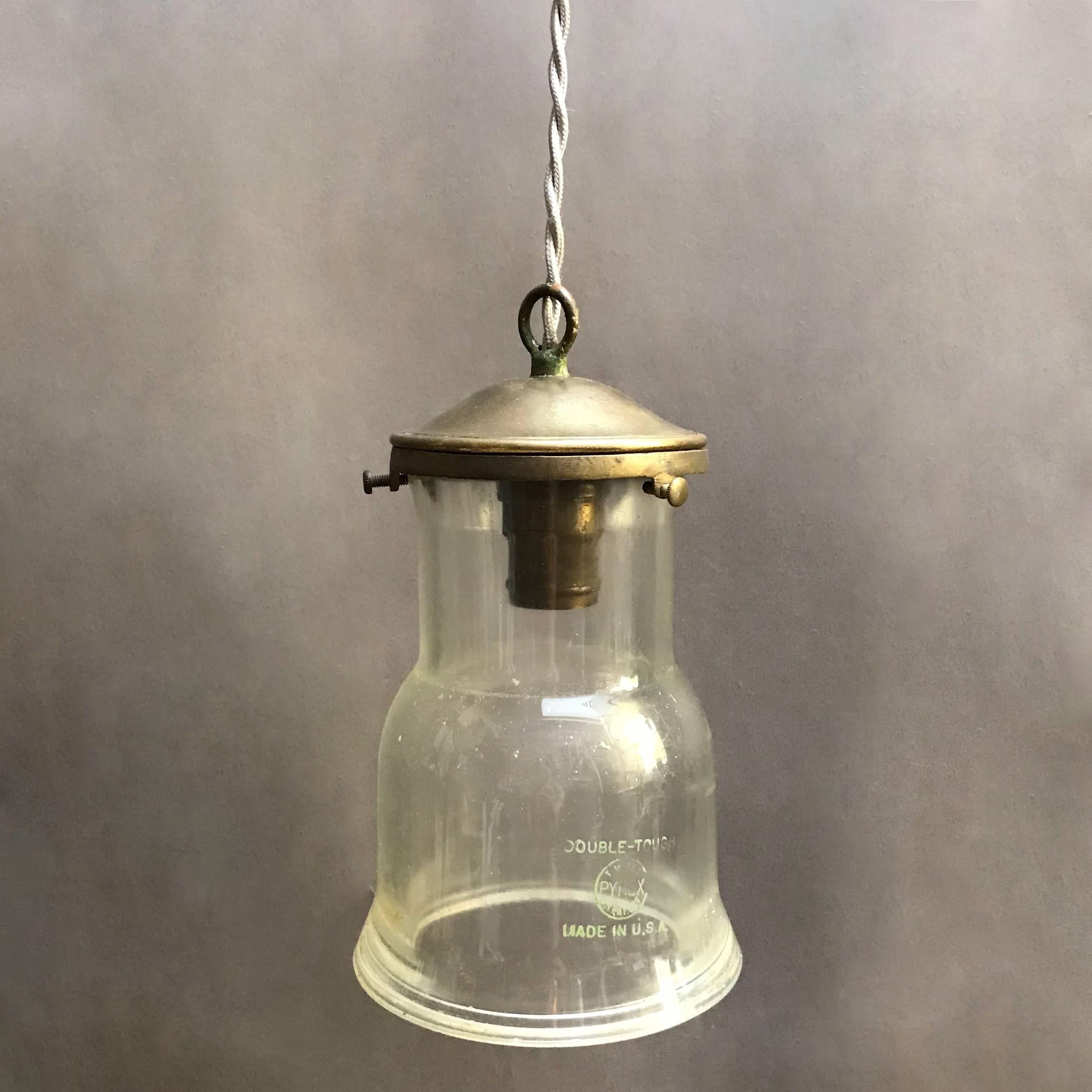 Custom, industrial pendant light features a Pyrex glass shade with brass fitter is newly wired with 36 inches of grey braided cloth cord to accept up to a 150 watt bulb.