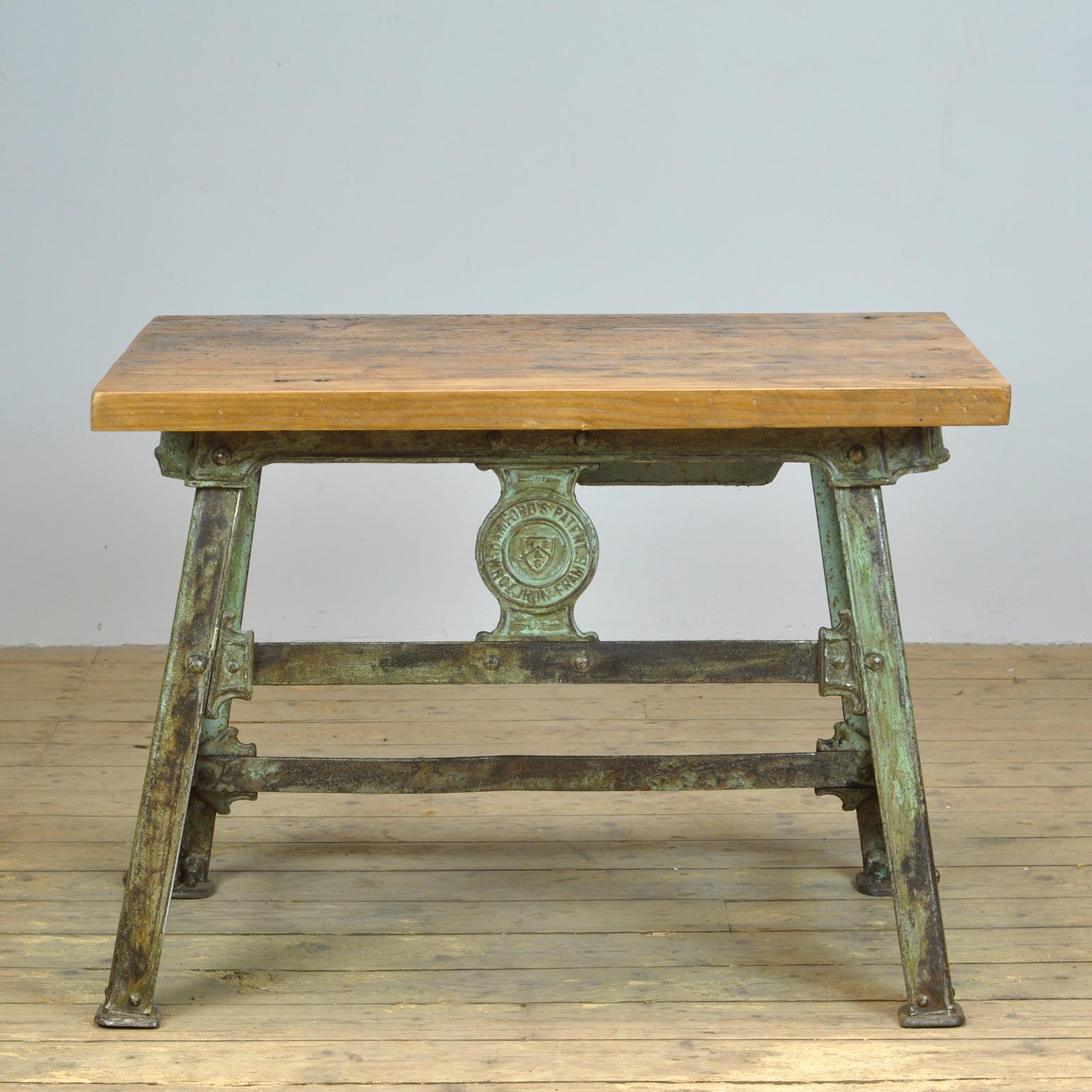 Industrial table made of a cast iron riveted base and a wooden top. The base is made by the English company Bamfords Ltd. circa 1900. The company logo can be seen on the base (BAMFORD'S PATENT WROT IRON FRAME). The top was added later. Heavy