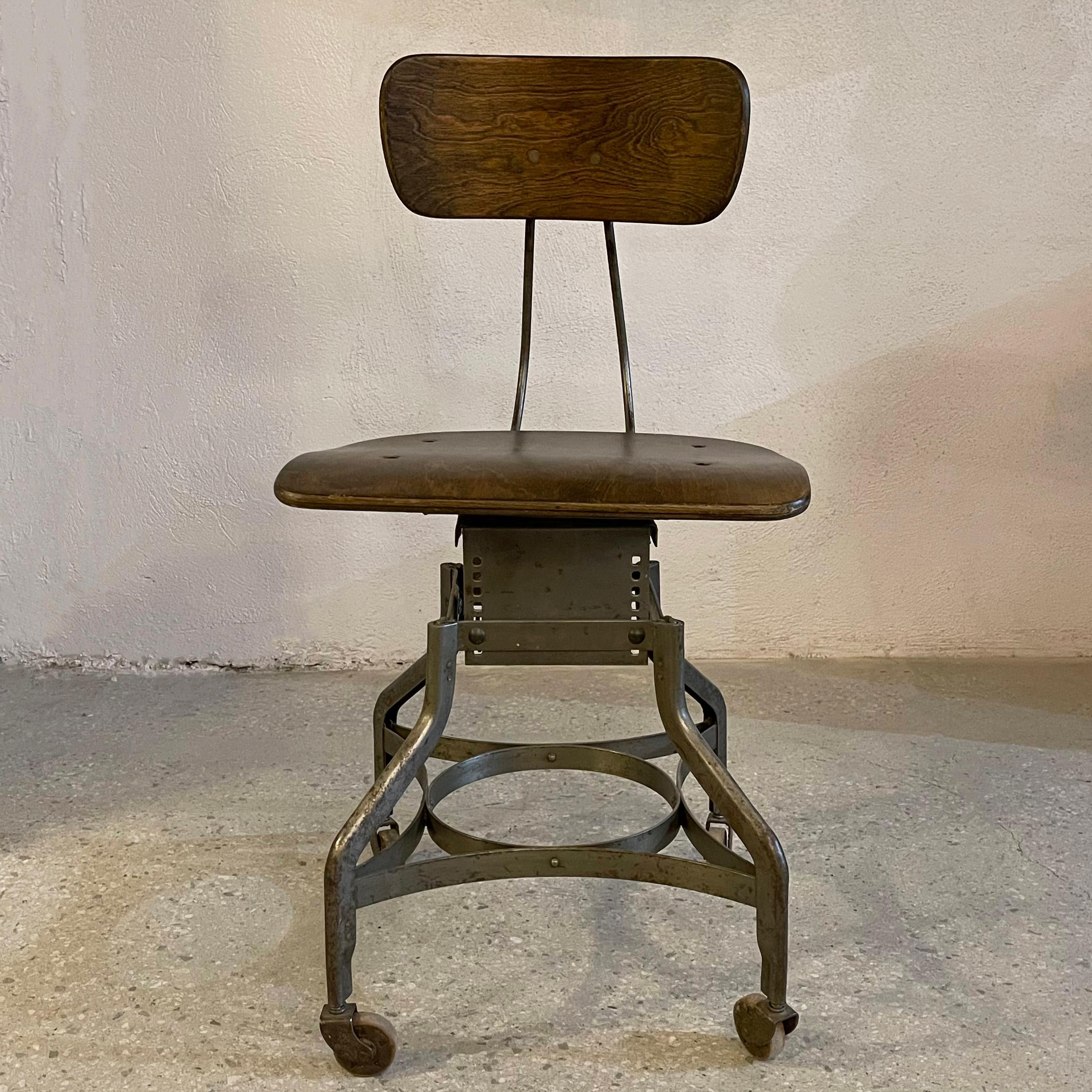 Industrial, rolling, swivel desk chair by the Toledo Metal Furniture Co. features a signature Toledo star, brushed steel base with bent birch ply seat and back. The height is adjustable in 7 increments from 16 - 19 inches by setting the plate under