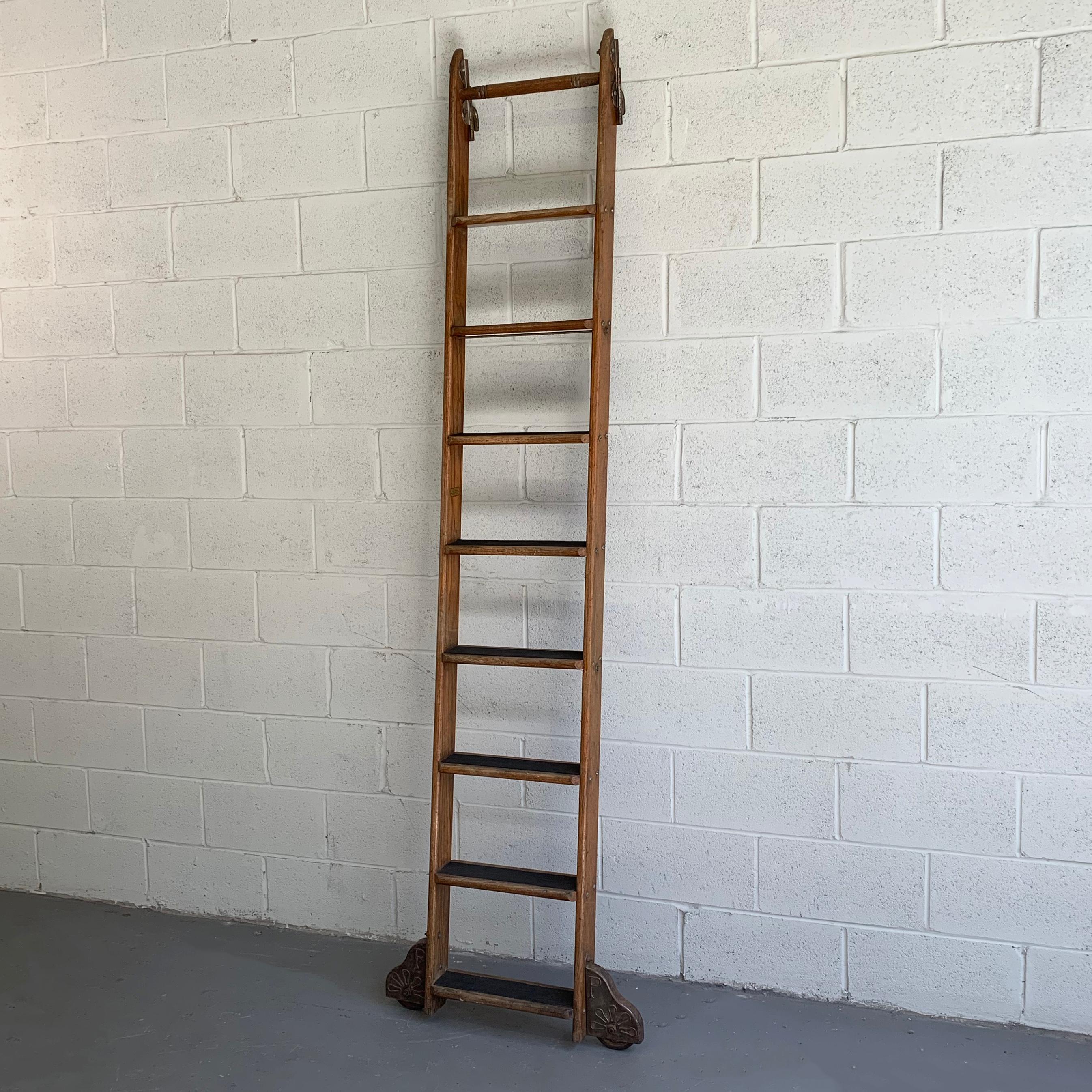 Industrial, rolling, oak library ladder by Putnam features decorative steel hardware, hooks at the top and lateral wheels at the bottom that measure 27 inches wide.