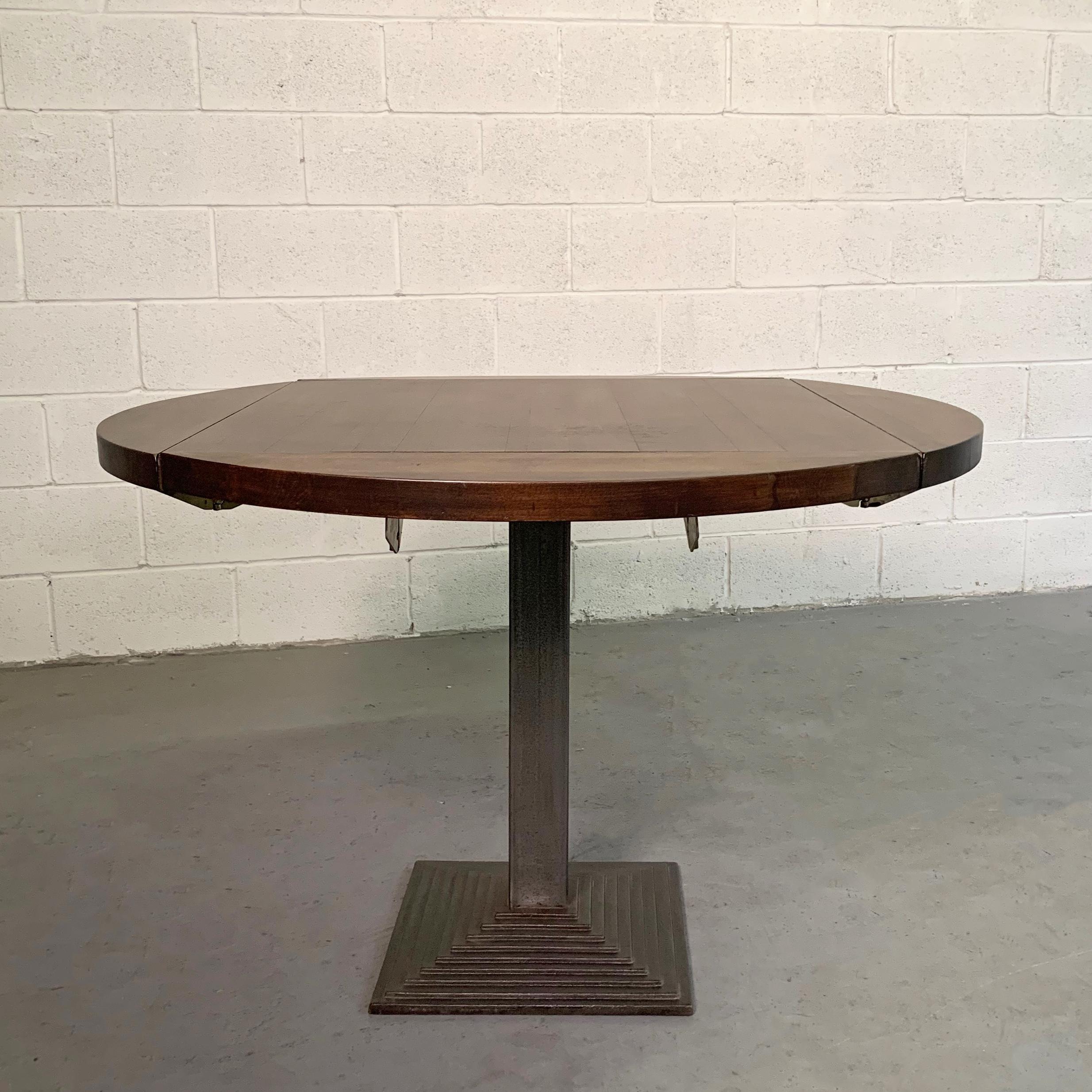 Custom, industrial, round, oak dining table with cast iron pedestal base folds on four sides to a smaller 30 inch square table.