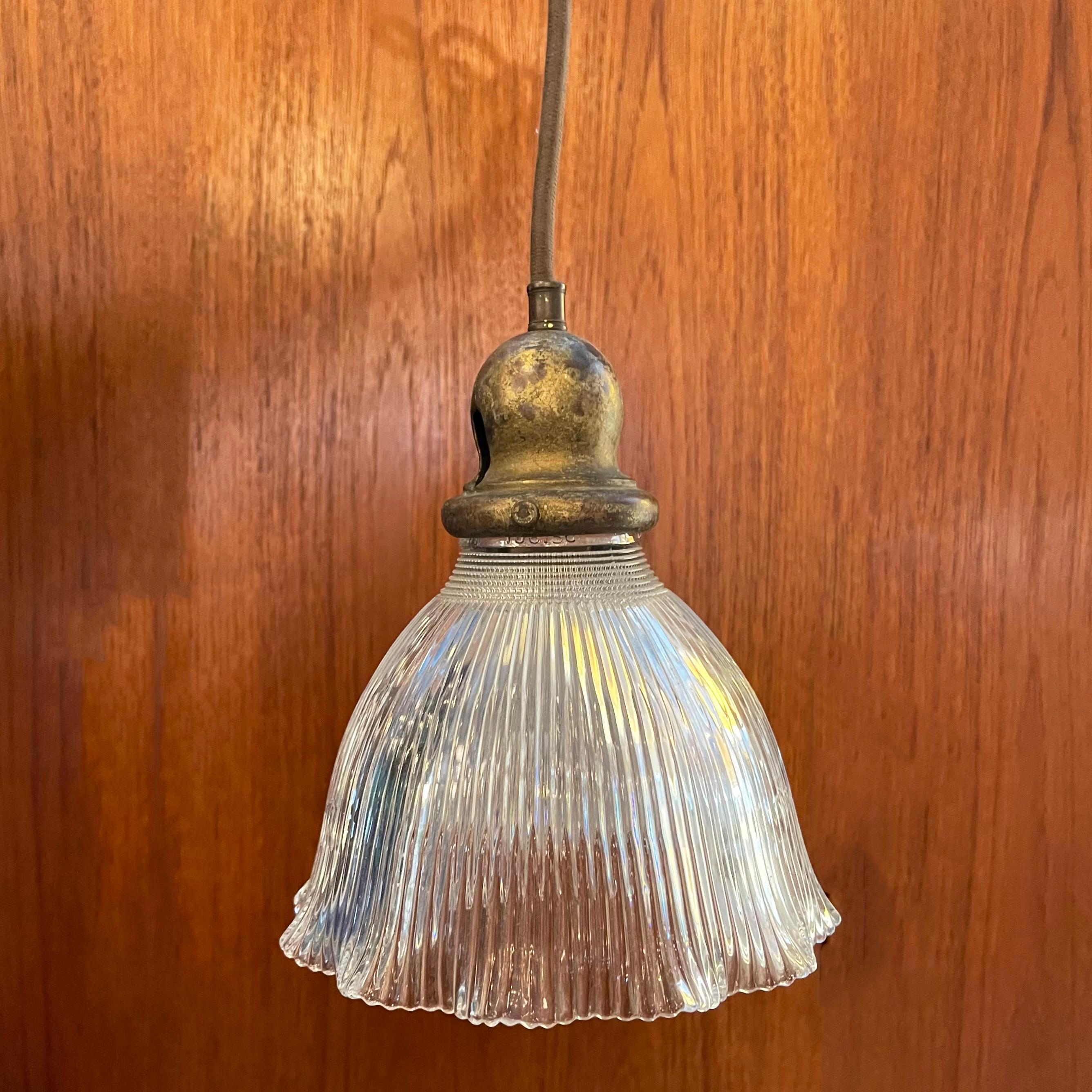 Industrial pendant light features a ribbed Holophane bell shade with ruffle trim on a brass fitter, newly wired with 40 inches of brown cloth cord to accept a medium socket bulb up to 75 watts.