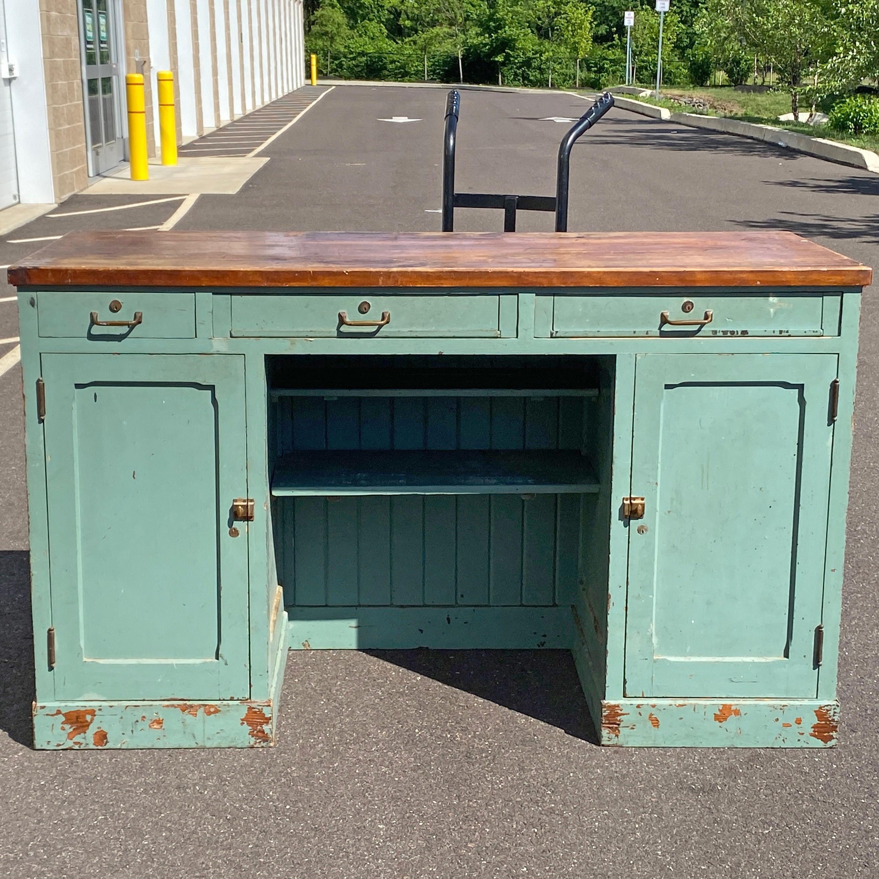 An amazing one of a kind standing desk or workstation salvaged from a Pennsylvania post office featuring three drawers above two closed cabinets with adjustable shelves and a finished back. The kneehole also has two half shelves in the back that are