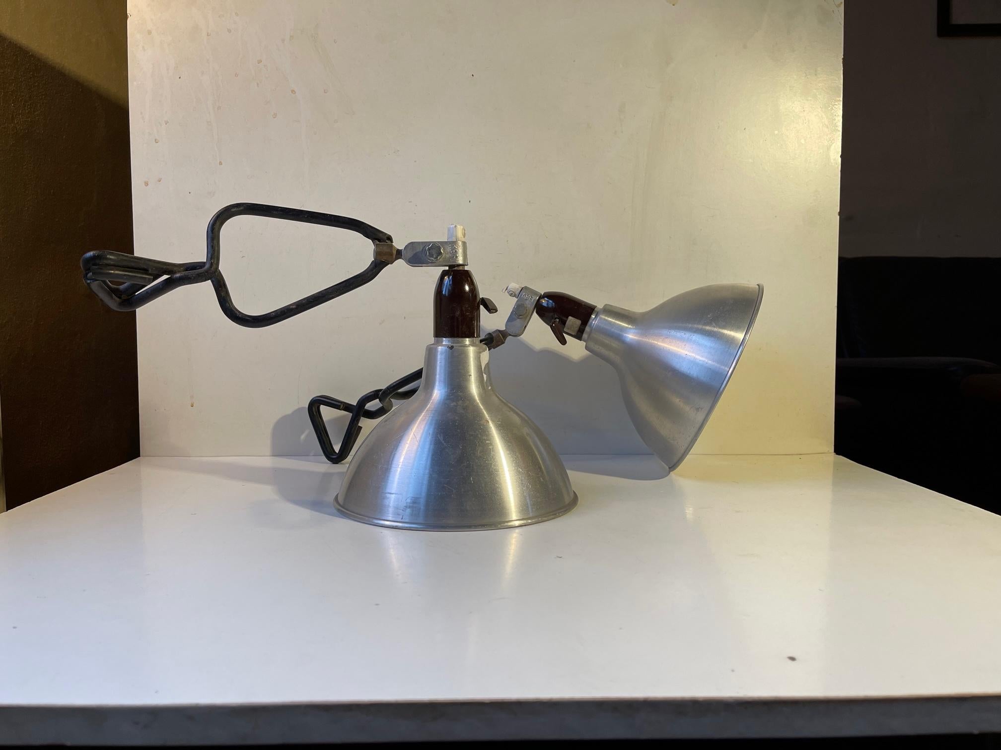 A pair of versatile and multi-adjustable clamp sconces. Manufactured by Køfi design in Denmark during the 1950s or 60s. This particular set came out from a closed Motorcycle repair shop that operated from the 1940s to the 1990s on the west coast of