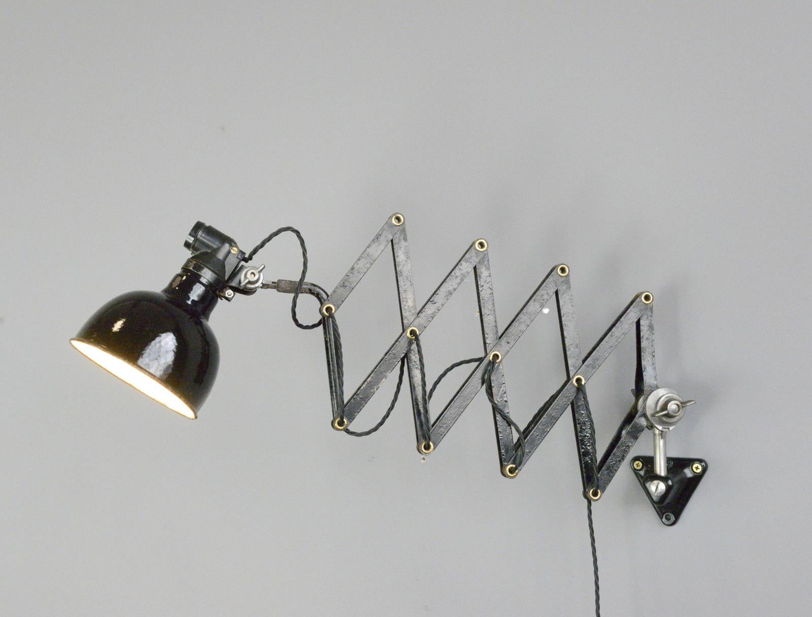 Industrial scissor lamp by Rademacher, Circa 1930s.

- Vitreous black enamel shade
- Original bakelite switch on the shade
- Extendable scissor mechanism with brass details
- Takes E27 bulbs
- By Rademacher, Dusseldorf
- German, 1930s
-